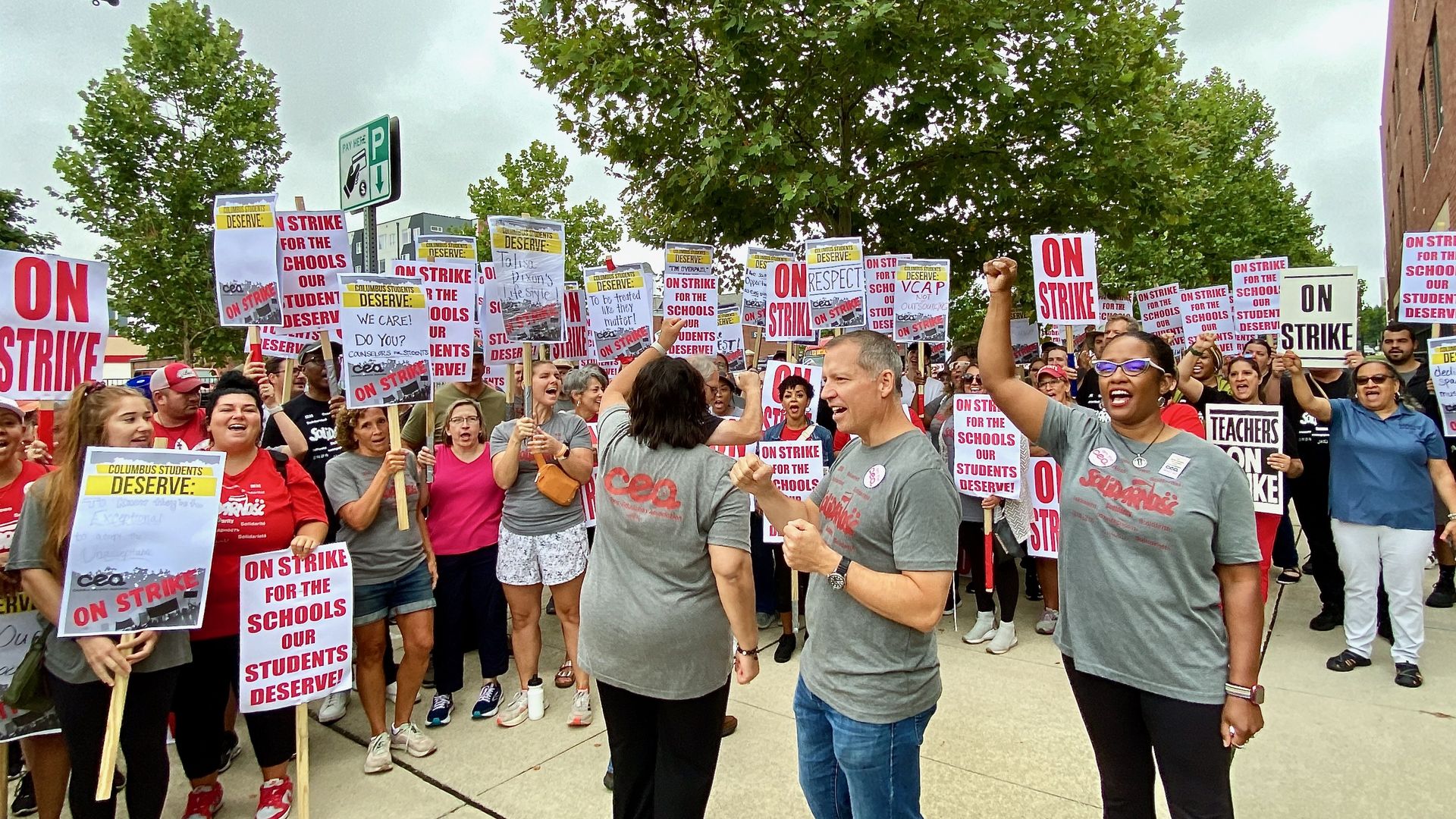 A crowd of teachers holds signs and cheers during picketing