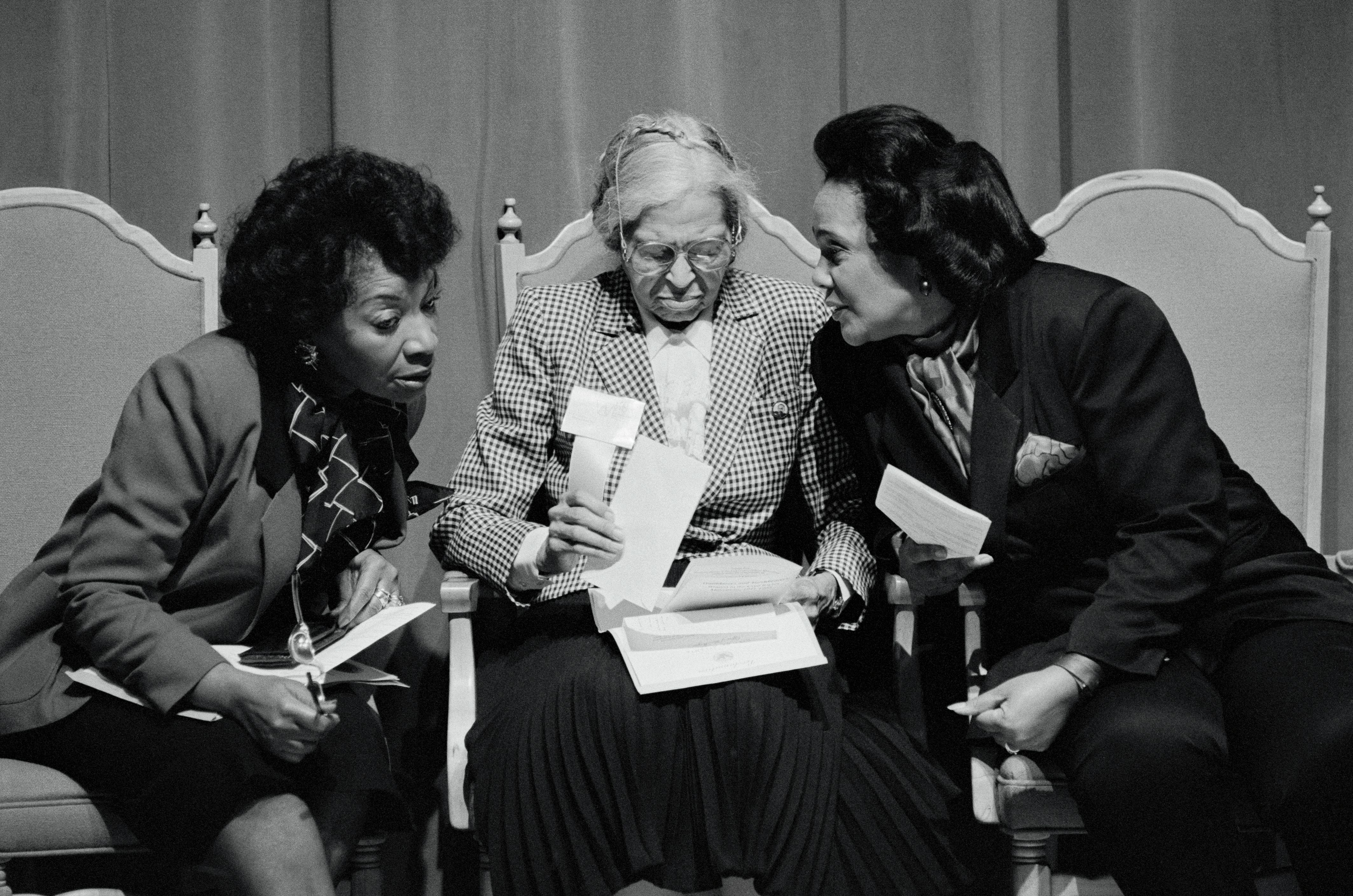 (Original Caption) Coretta Scott King (R), widow of slain civil rights leader Dr. Matin Luther King Jr., confers with Dr. king's sister, Christine King Farris (L) while Rosa Parks, the Black woman who sparked the Civil Rights movement, goes over her notes prior to her speech 10/13 at the MLK Center. The occasion was a tribute to parks, the "Motehr of the Civil rights movement," which began when the black seamstress refused to giver her bus seat up to a white passenger in 1955.