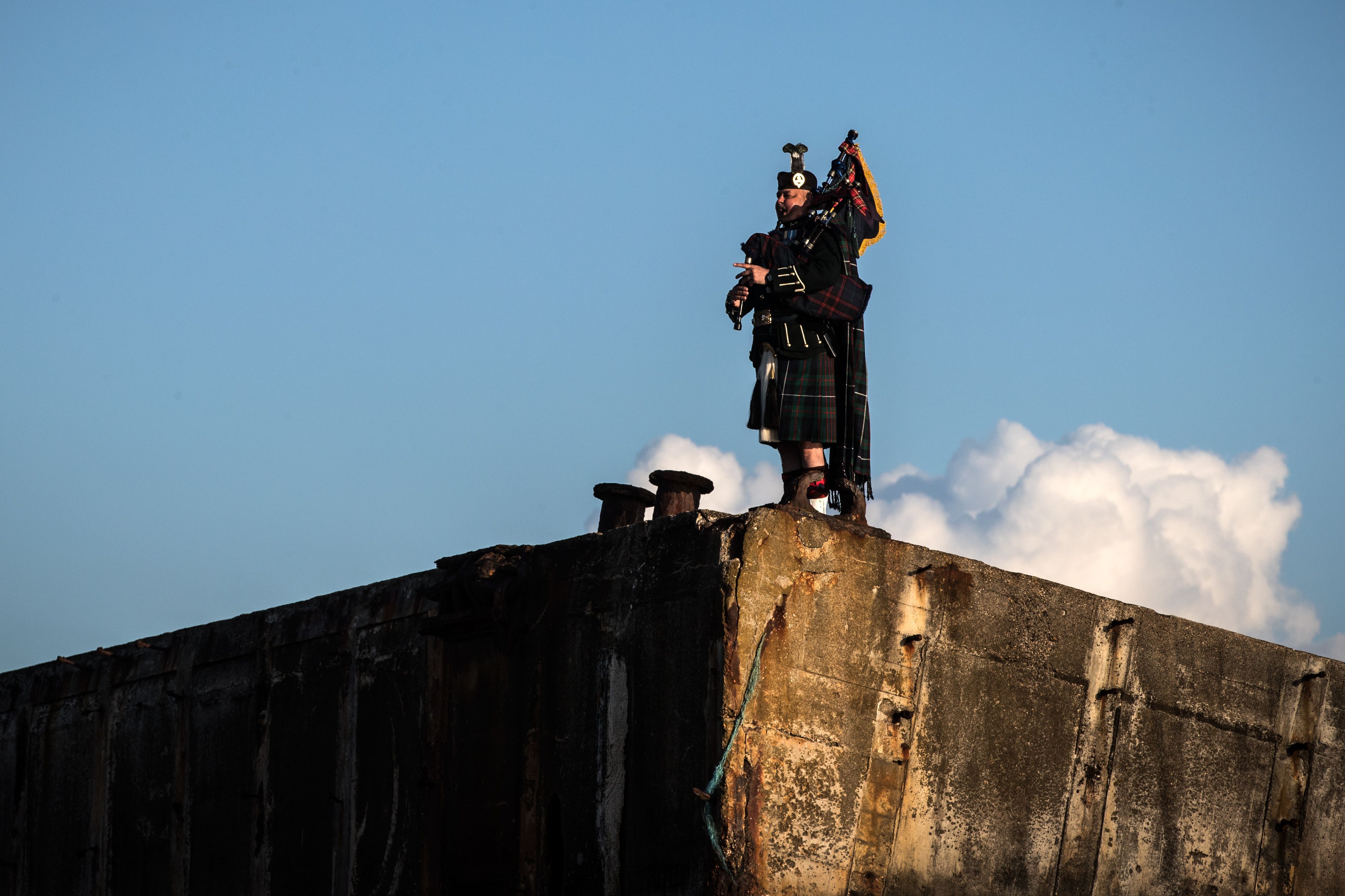 A bagpiper plays on a vestige of the atlantic wall on the beach of Arromanches on June 6, 2019.