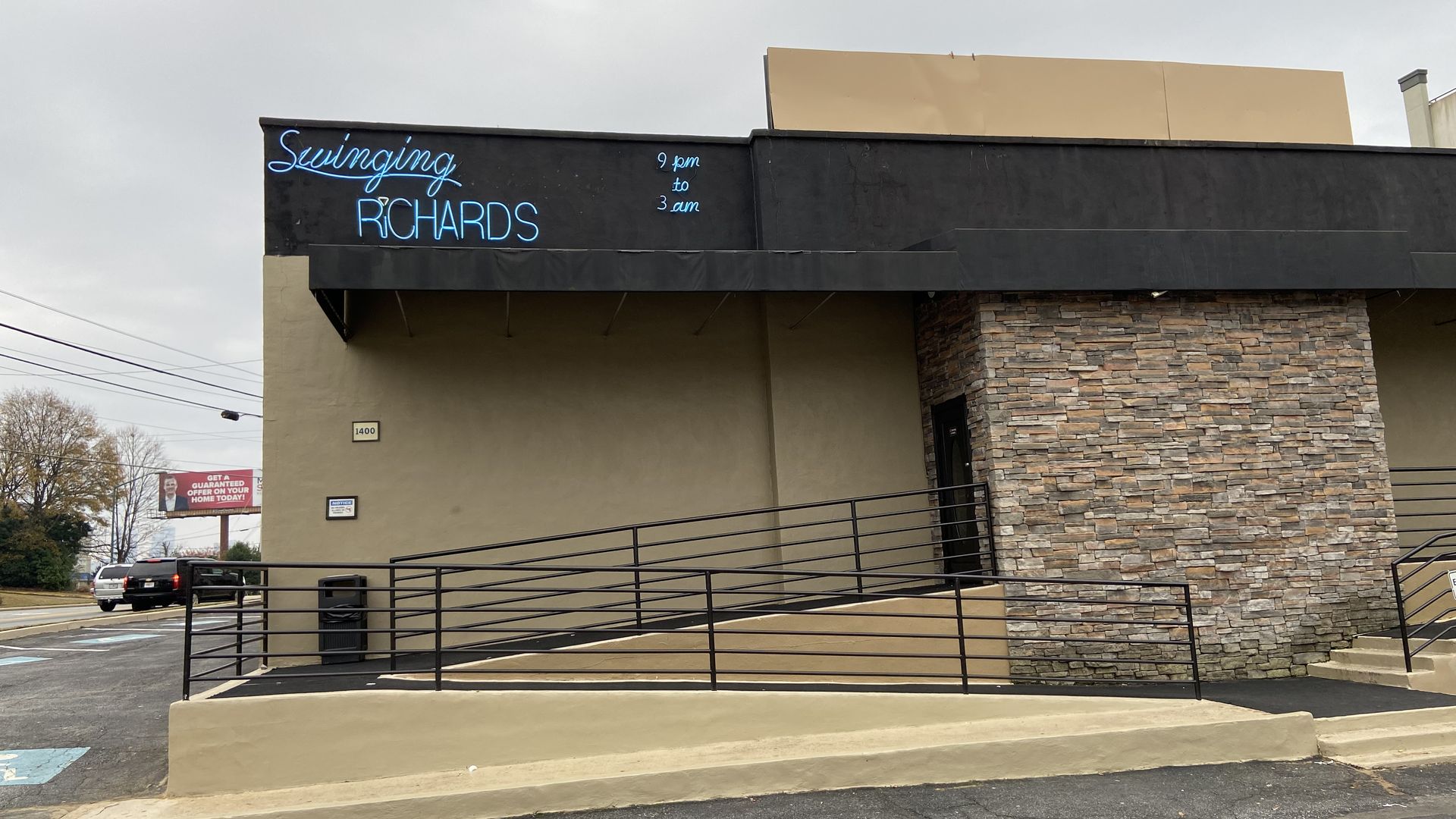 A squat building with no visible windows and a neon sign that says "Swinging Richards"