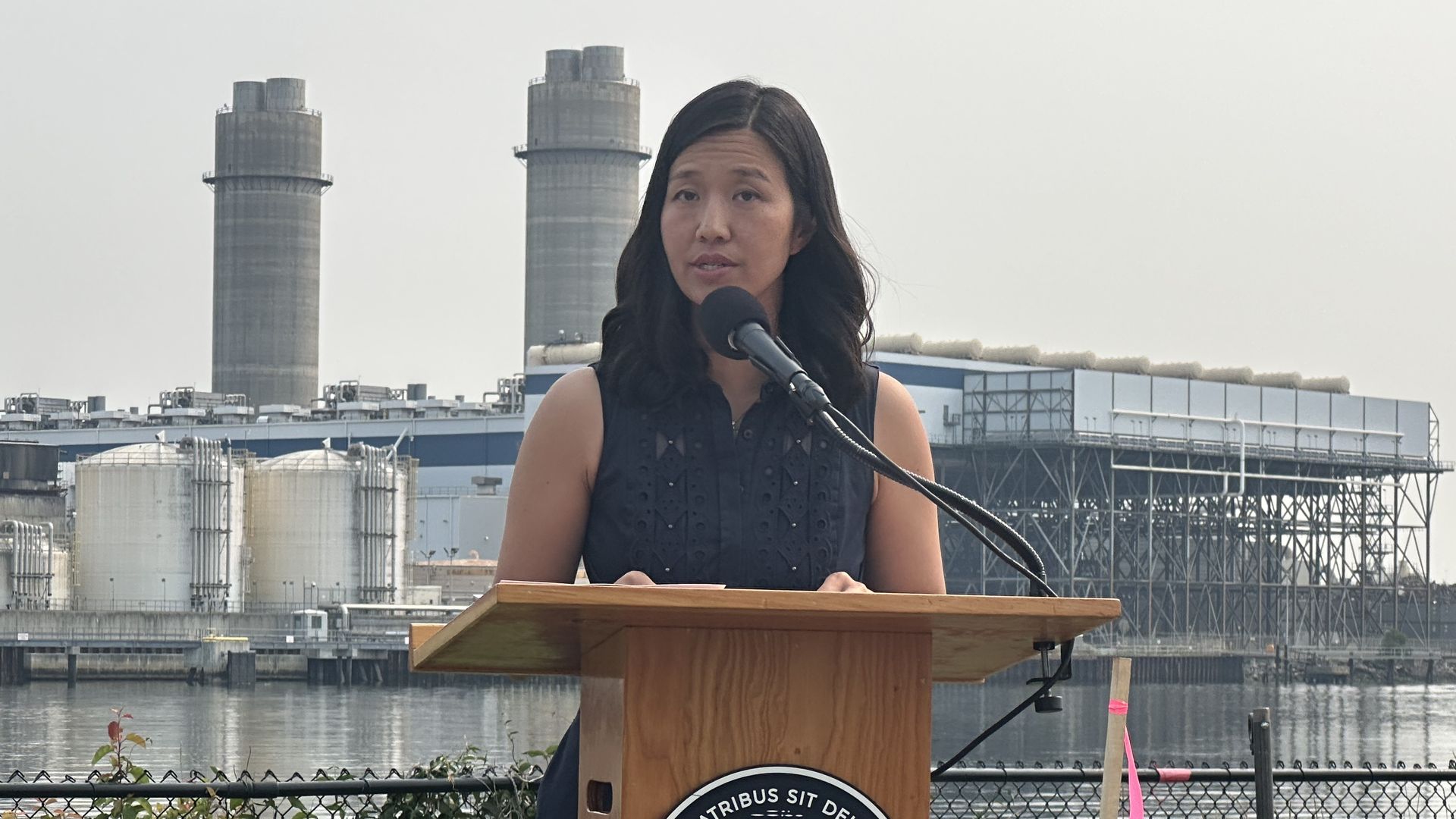 Mayor Michelle Wu speaks at a lectern while leading a press conference in Charlestown across the river from the proposed New England Revs soccer stadium.