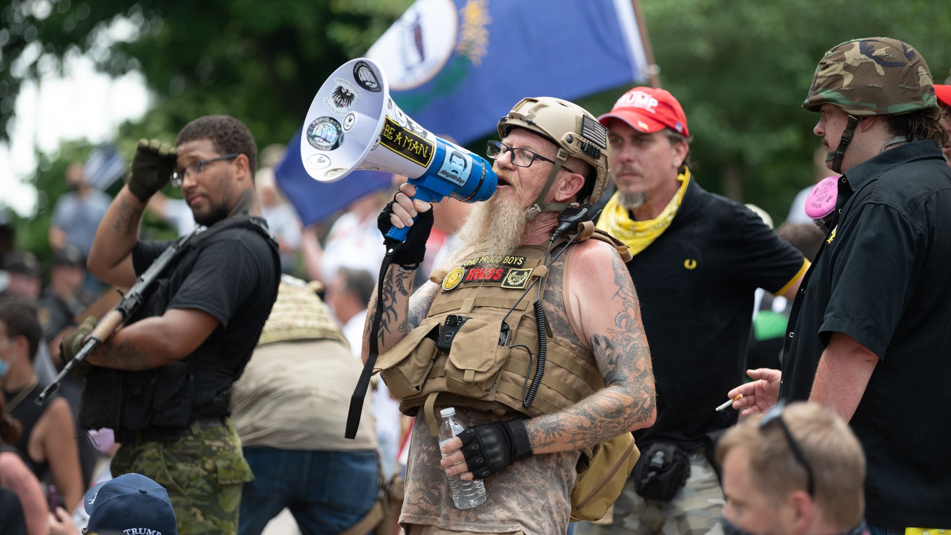 A man wearing a bulletproof vest speaks into a megaphone at a protest