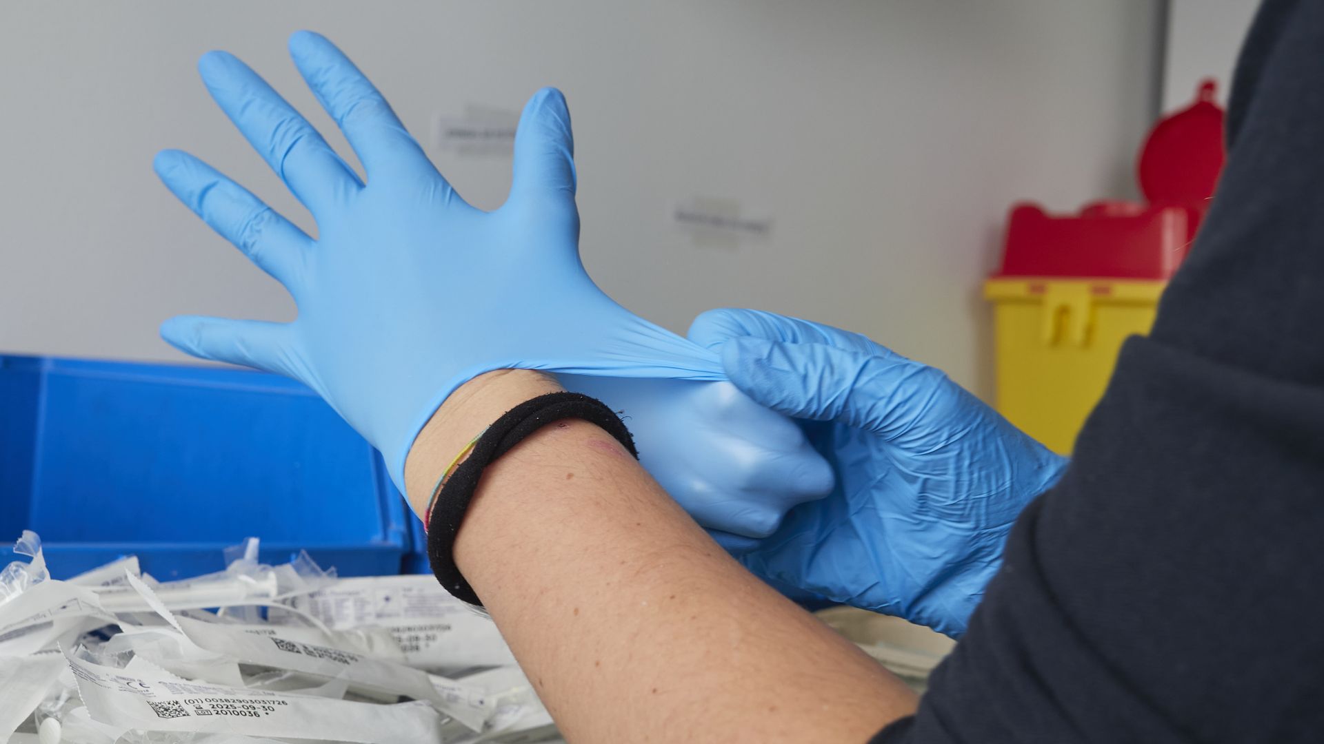A health professional puts on nitrile gloves.