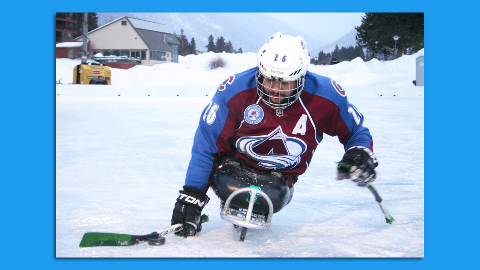 A man rides a sled skate while using his two arms to propel himself forward while on stop of a frozen lake. 