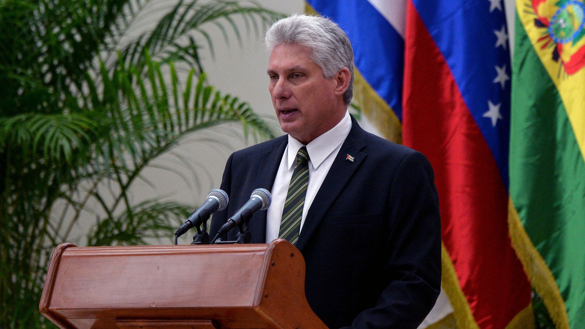 Miguel Diaz-Canel speaking at a lectern in front of Cuban flag