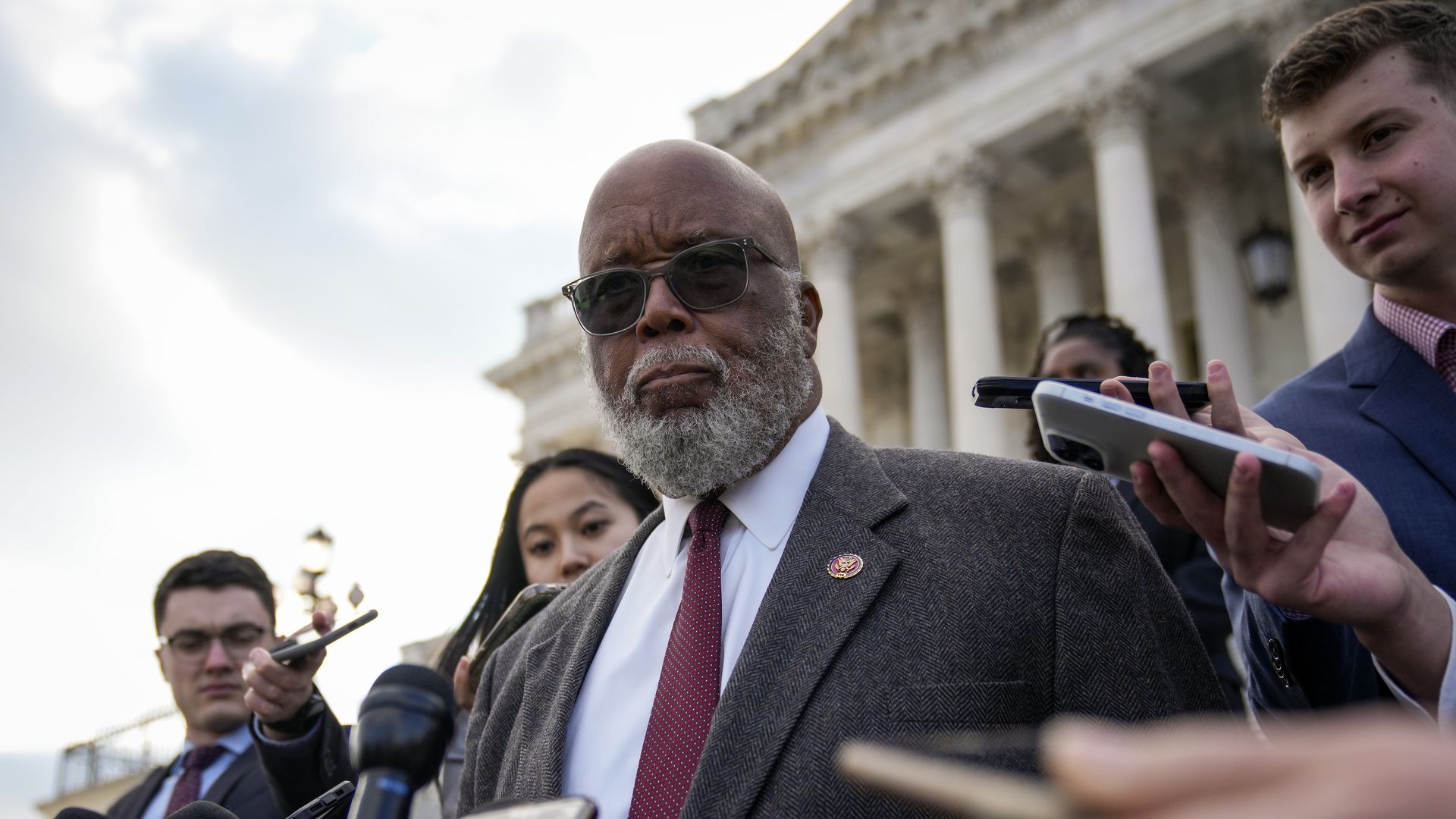 Rep. Bennie Thompson (D-Miss.), the chair of the Jan. 6 committee wearing a grey suit, light blue shirt and red tie, speaks to reporters on the Capitol steps.
