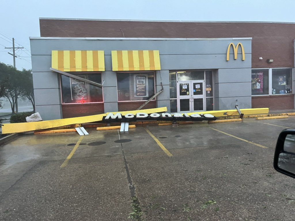 A McDonald's sign is seen laying across the ground in front of a restaurant.