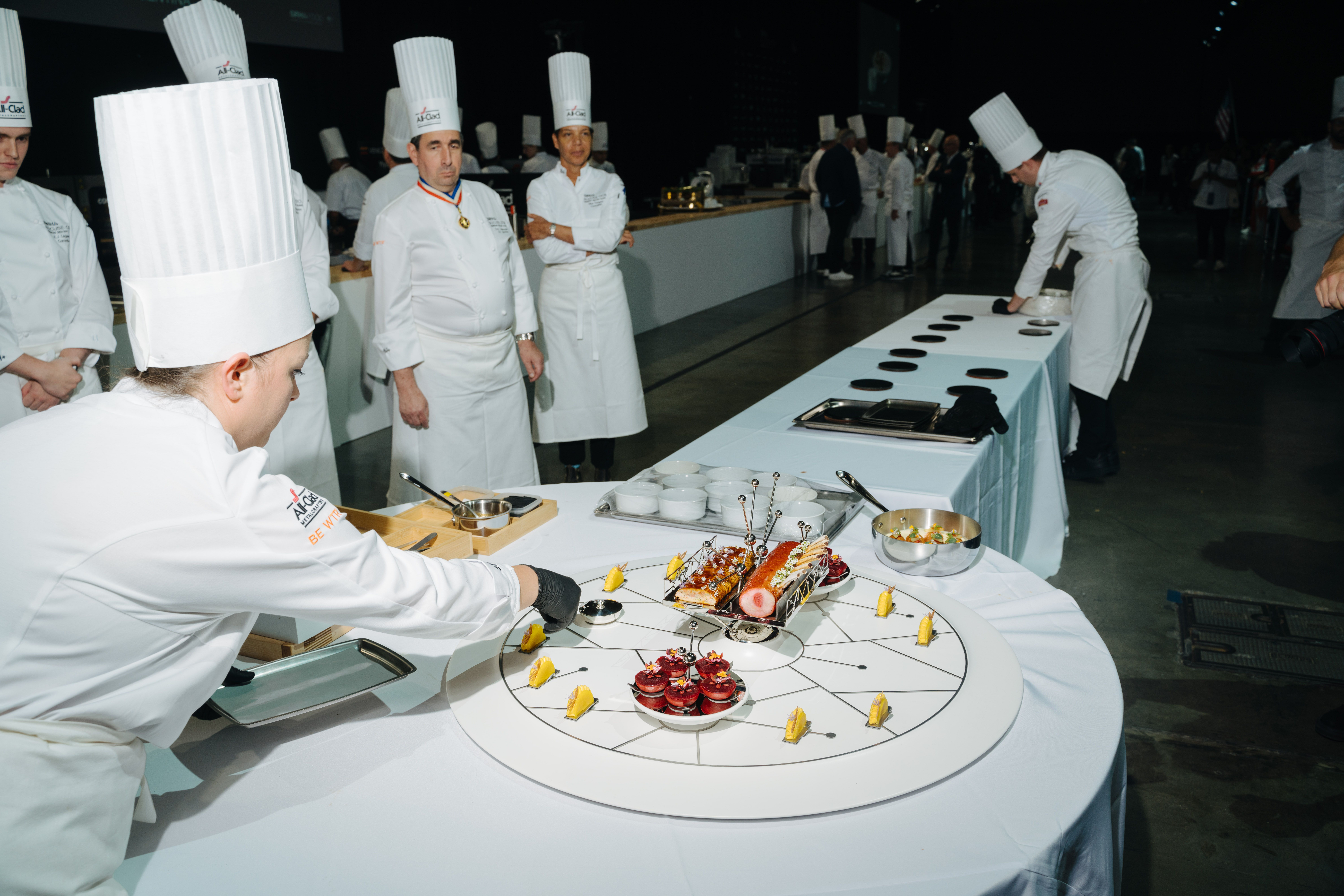 Chef Stefani De Palma puts a finishing touch on a platter presentation as other chefs look on.