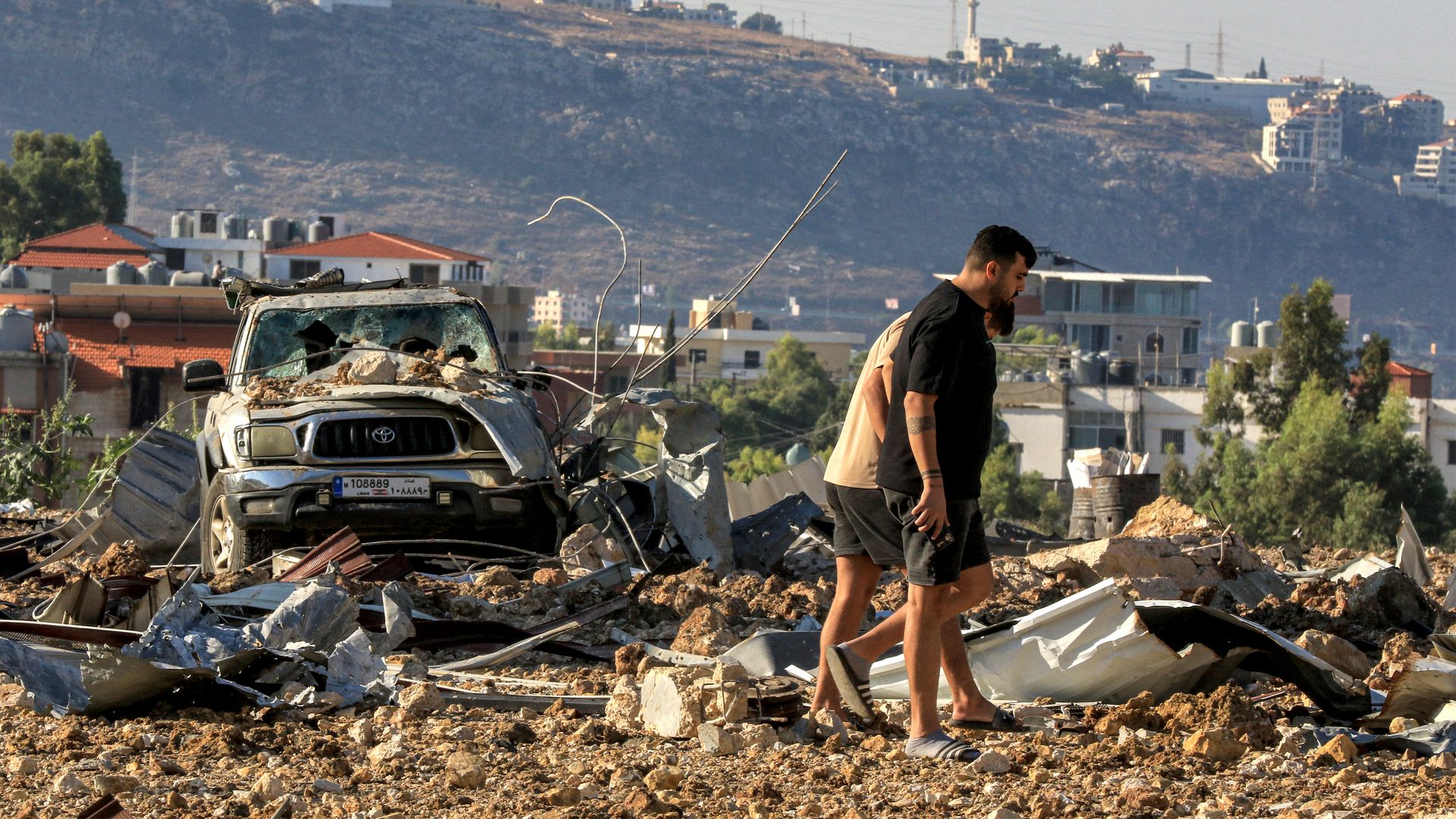 People inspect the site of an Israeli air strike in Jiyeh along the highway linking Beirut to the southern city of Sidon on September 25, 2024.