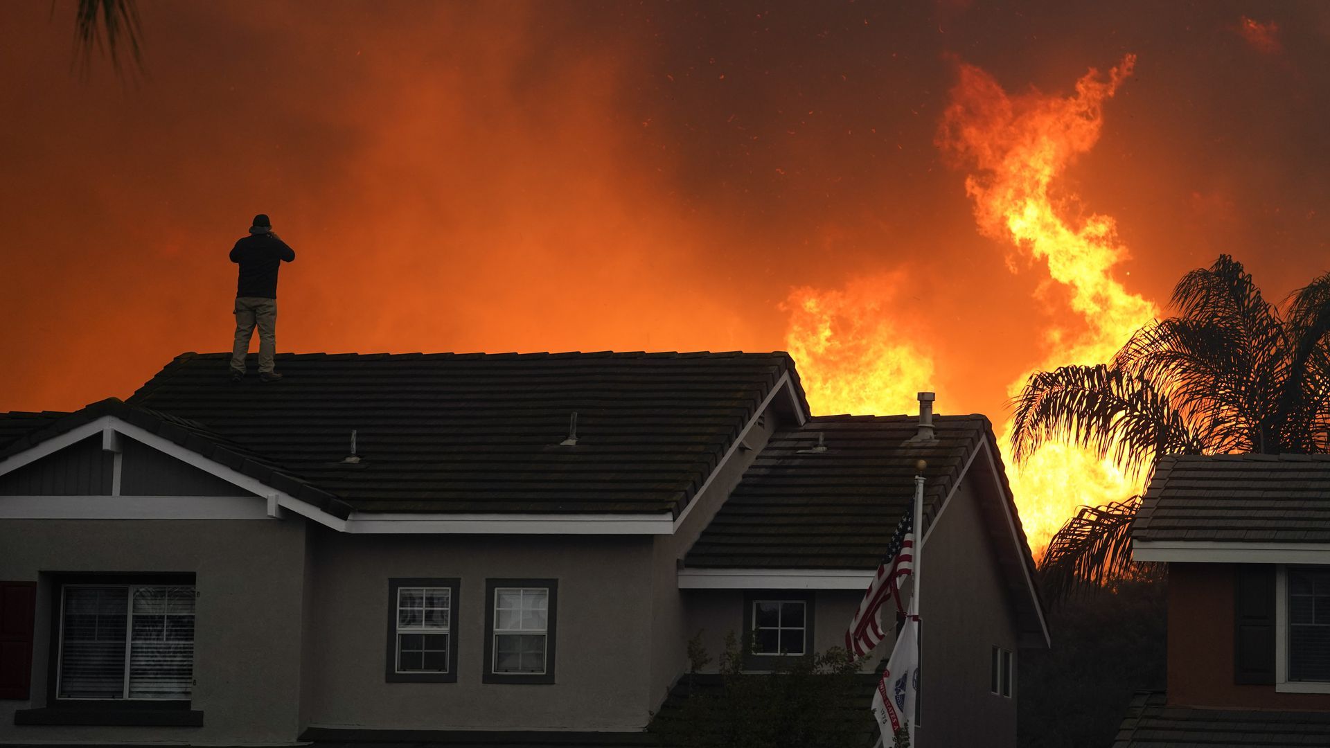 A resident stands on his roof as the Blue Ridge Fire burned back in October in Chino Hills, Calif.