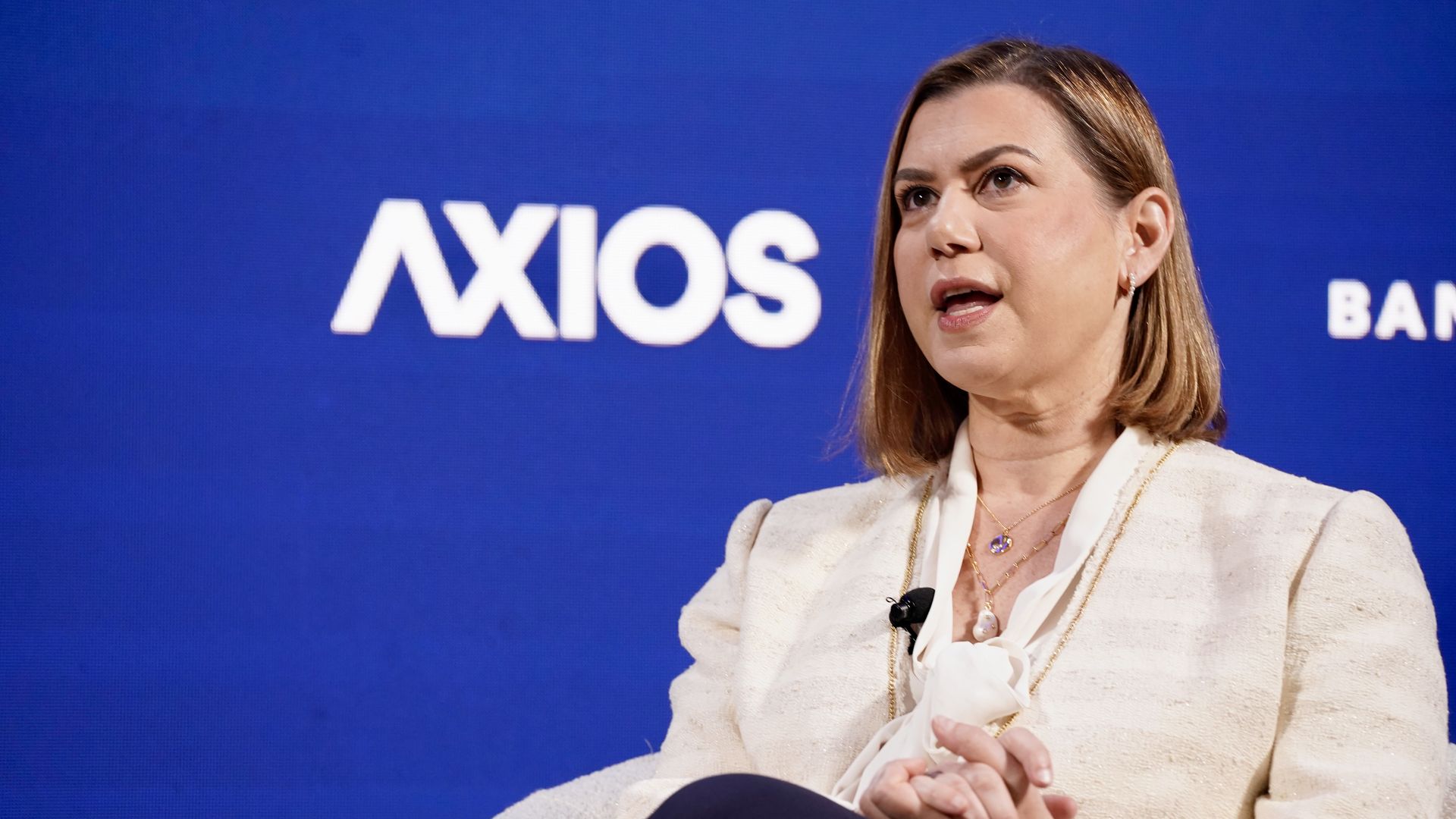 Sen. Elissa Slotkin speaks at an Axios event wearing a cream-colored blazer against a blue background.