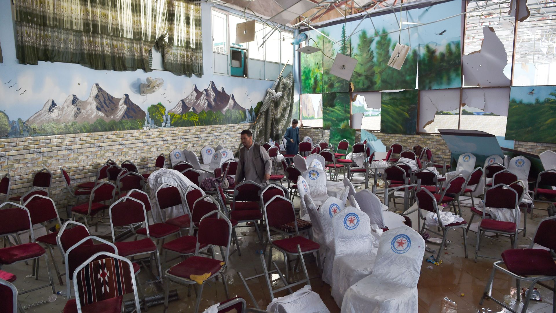 Afghan men investigate in a wedding hall after a deadly bomb blast in Kabul on August 18