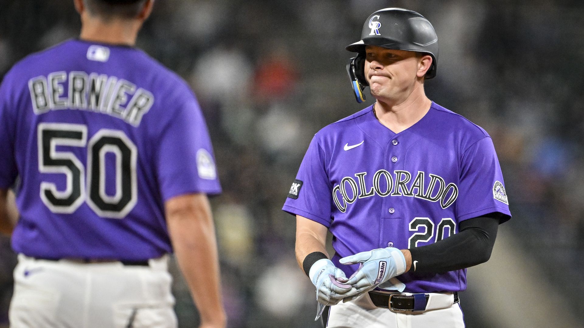 Two Colorado Rockies players in purple uniforms on a baseball field. One faces the other wearing a batting helmet; the left player's jersey reads Bernier and 60 on the back, with Colorado on the front.