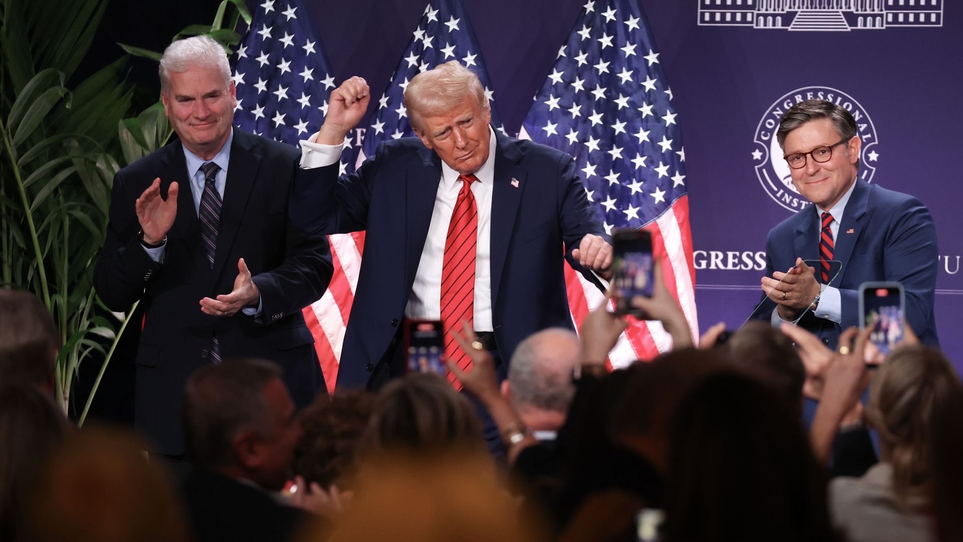 President Trump and Speaker Mike Johnson look on as a crowd cheers them.