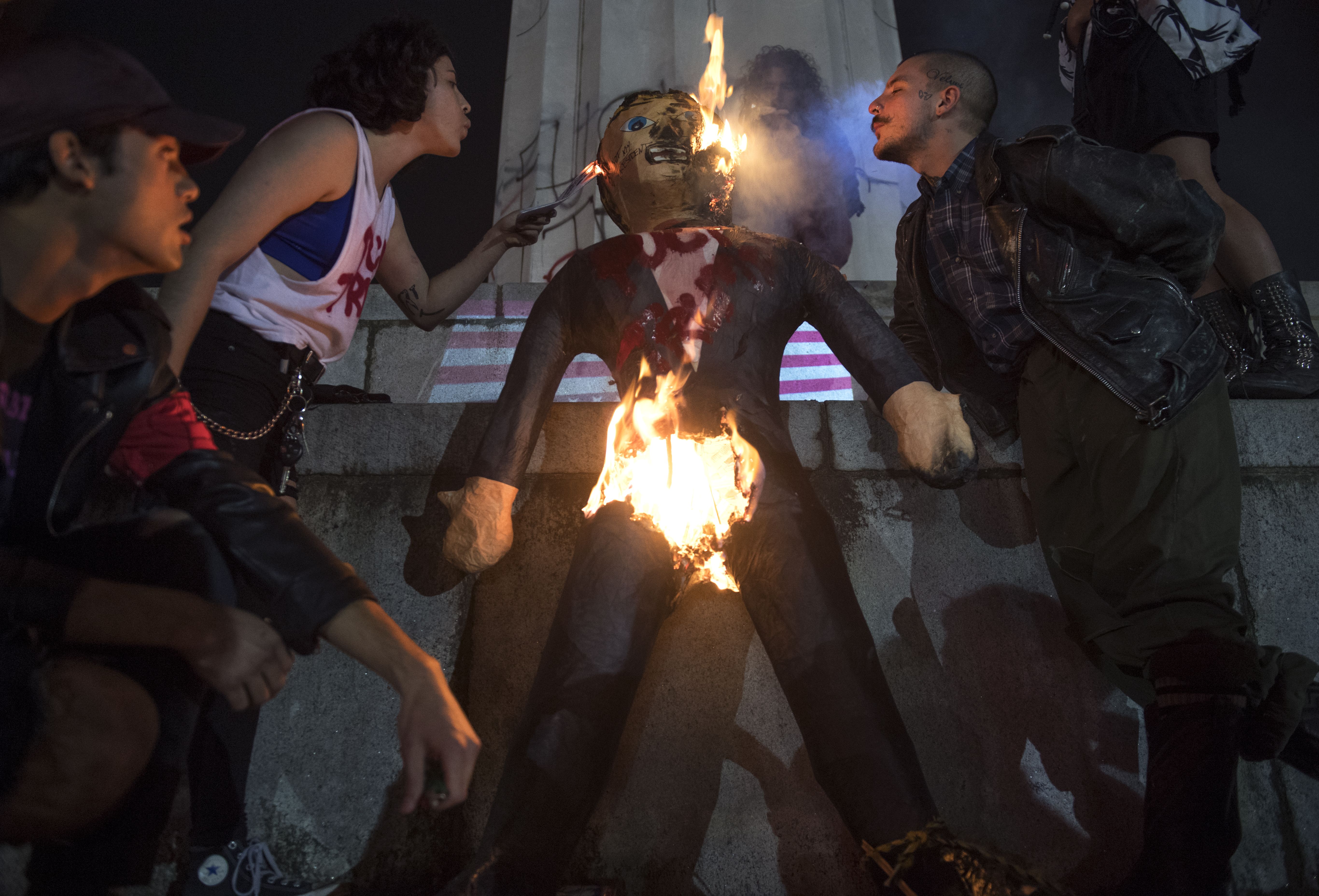 Protesters burn an effigy of Donald Trump in front of the Lee Circle monument.