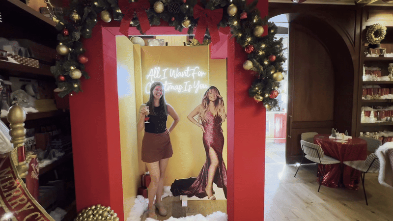  A woman smiles and wobbles her shoulders next to a cutout of Mariah Carey.