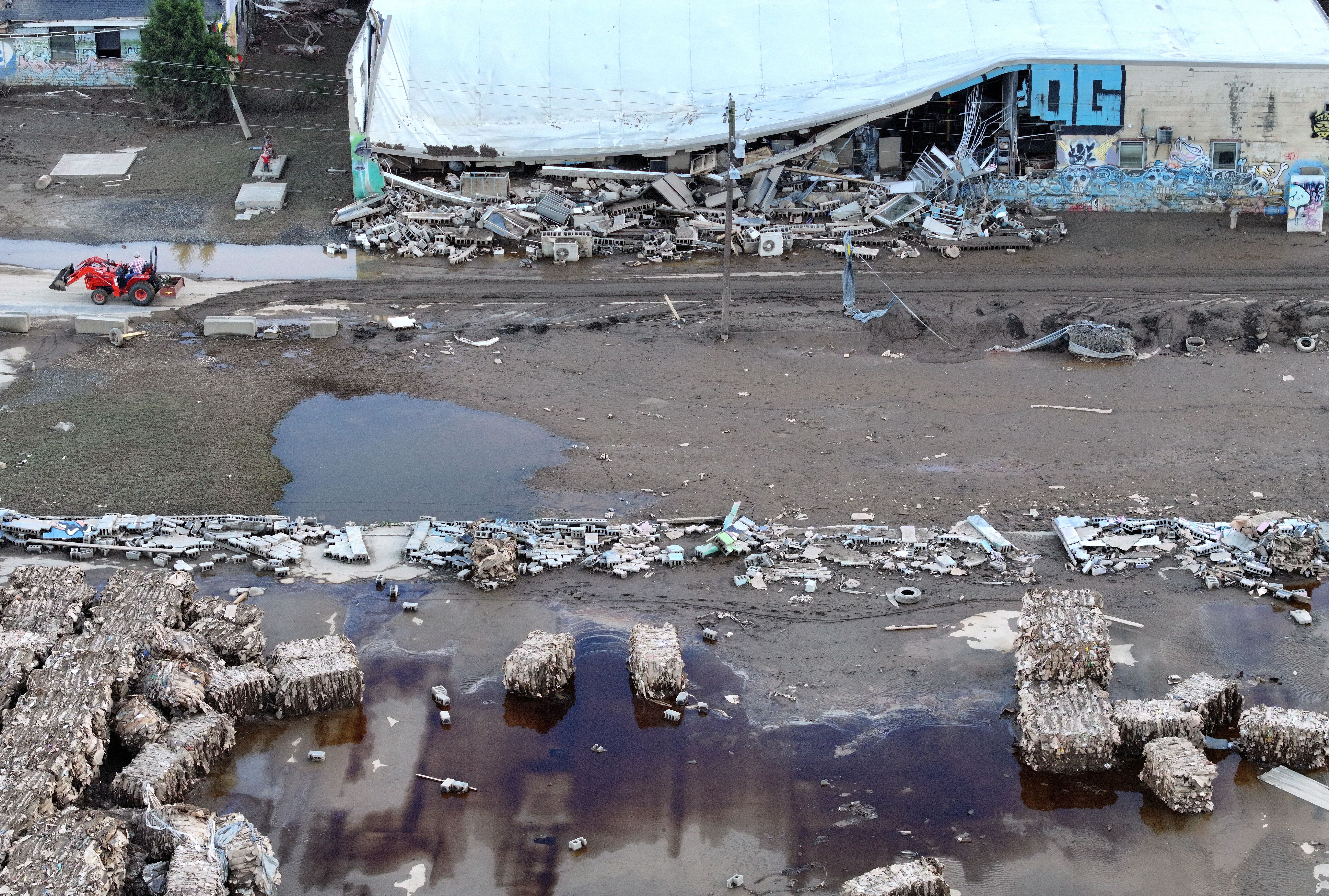 In an aerial view, a person drives a tractor while clearing debris in the River Arts District in the aftermath of Hurricane Helene flooding on October 2, 2024 in Asheville, North Carolina.