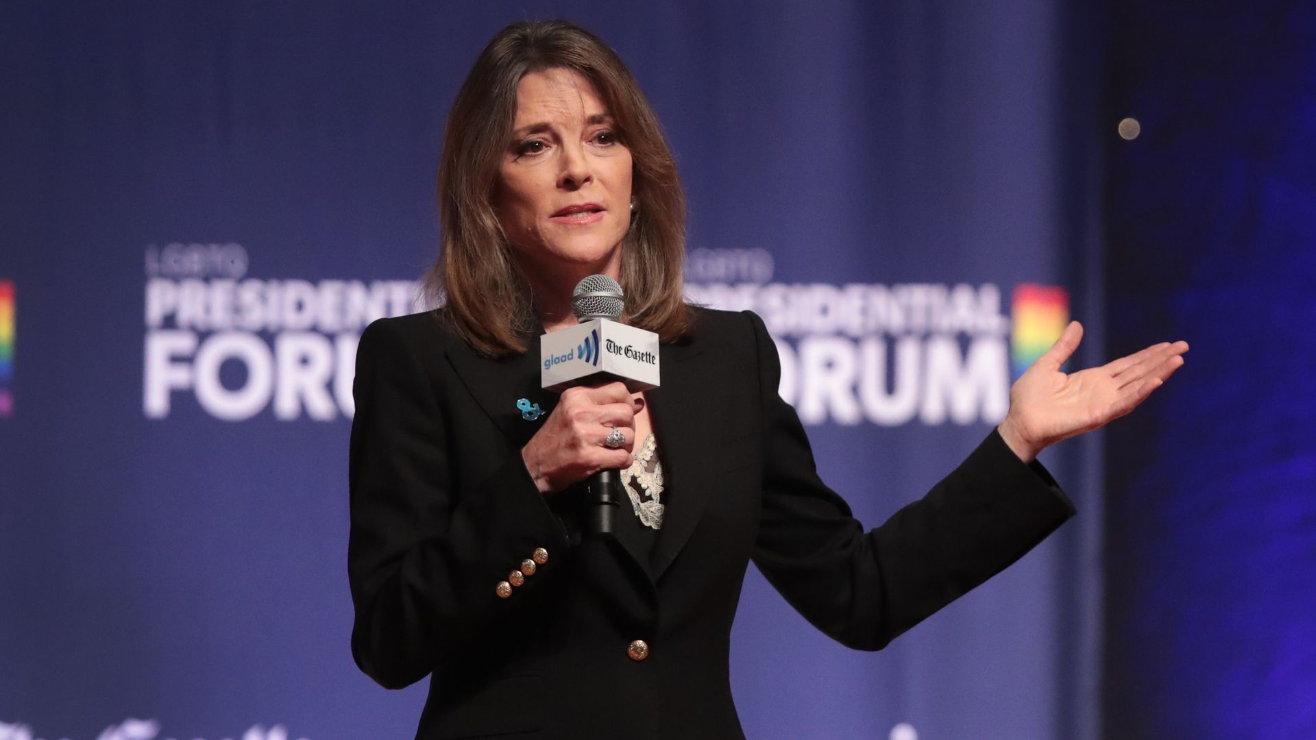 Marianne Williamson holds a microphone. 