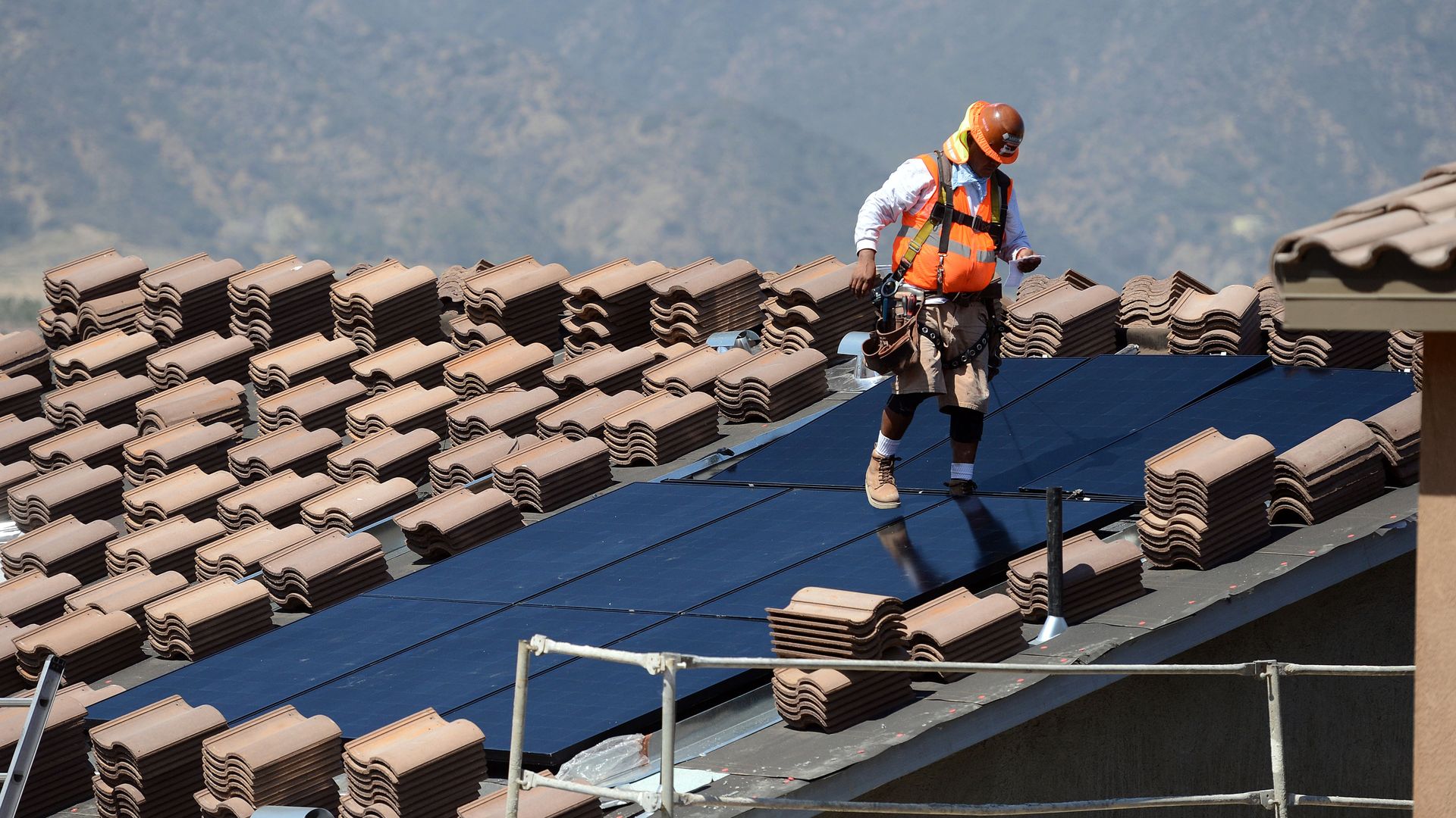 Workers install solar panels on the roofs of homes under construction south of Corona on May 3, 2018.