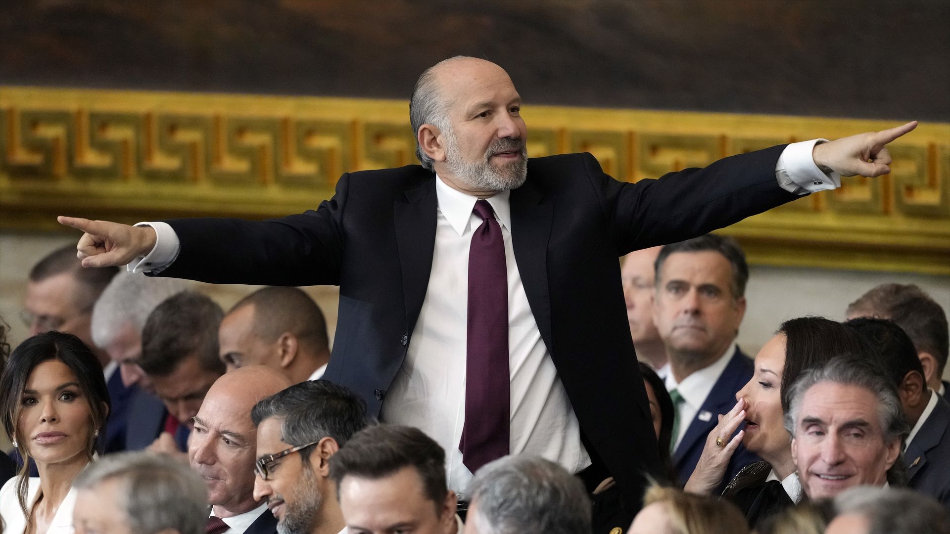 A person in a suit points with both hands