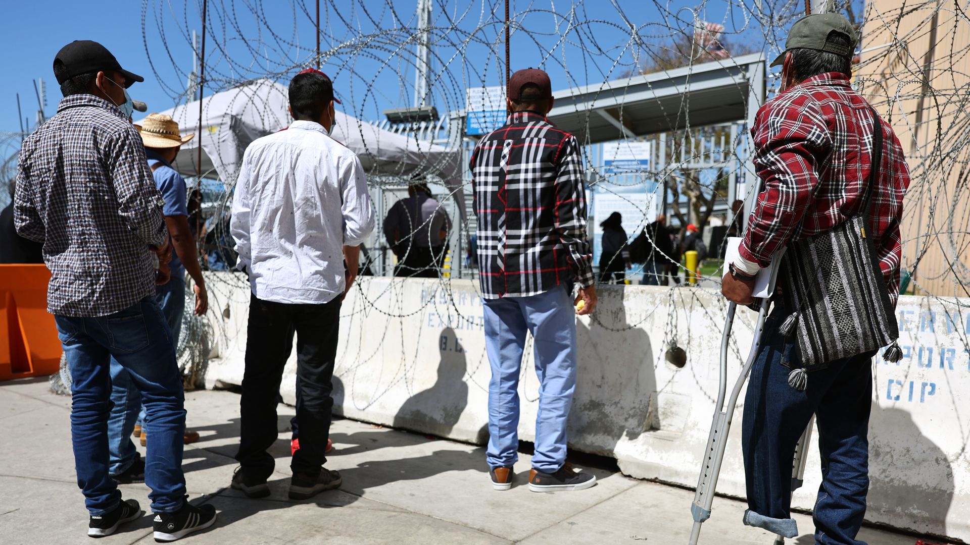 An asylum seeker from Mexico (R) waits outside the San Ysidro Port of Entry, which he hopes to cross to plead for asylum in the U.S.