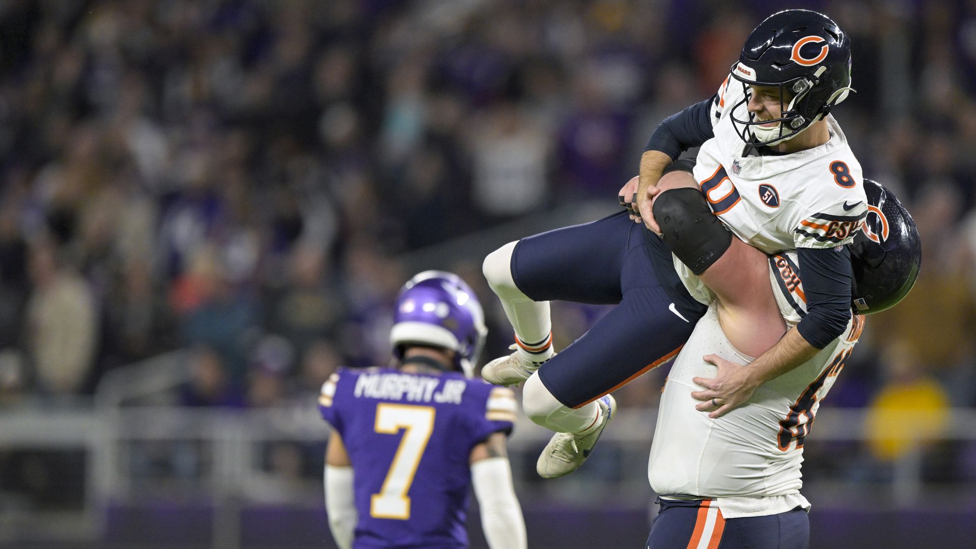 Photo of a football player lifting another football player off the ground in celebration
