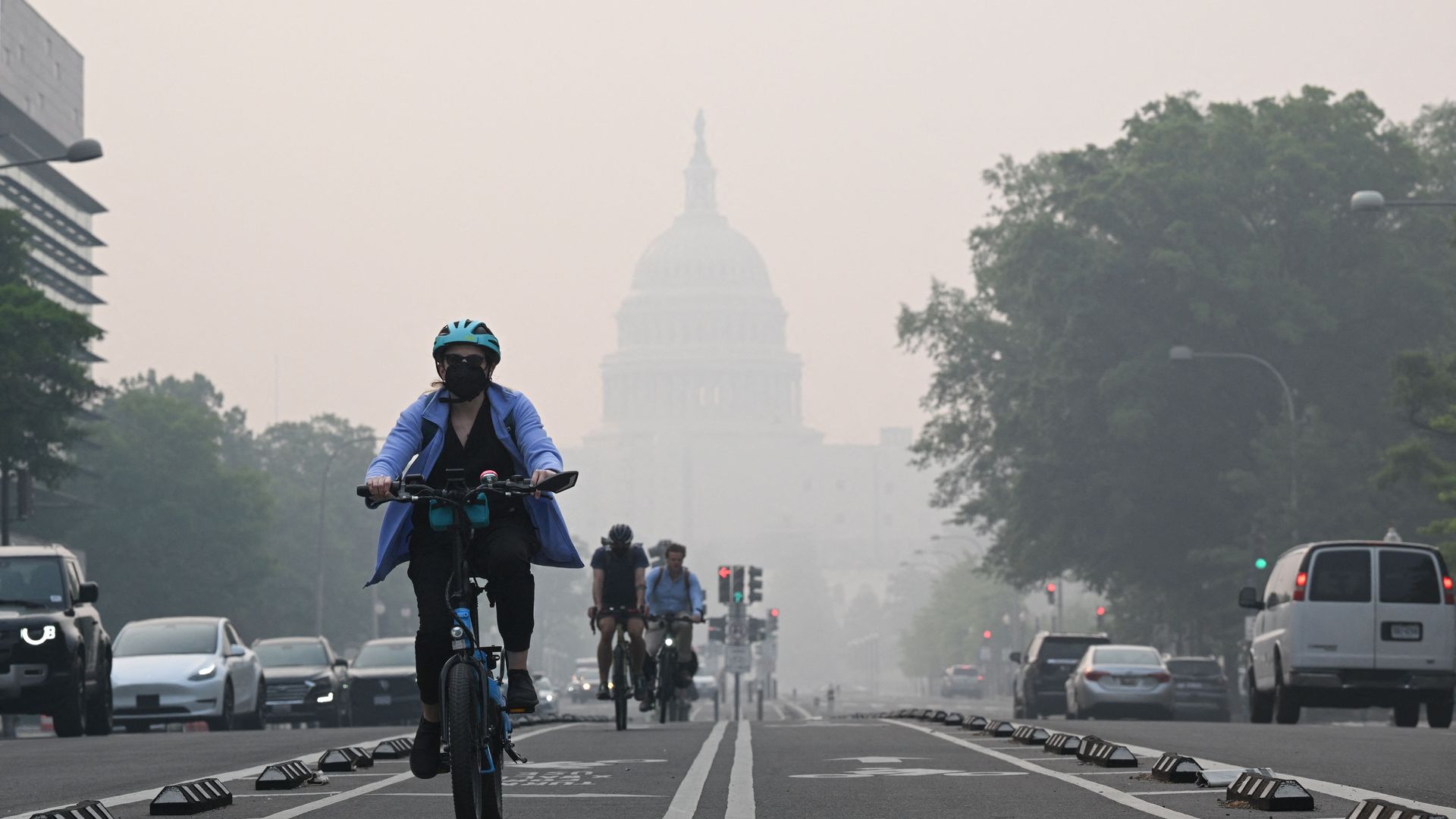 Cyclists ride on a street in front of the US Capitol Building as it is enveloped in wildfire smoke.