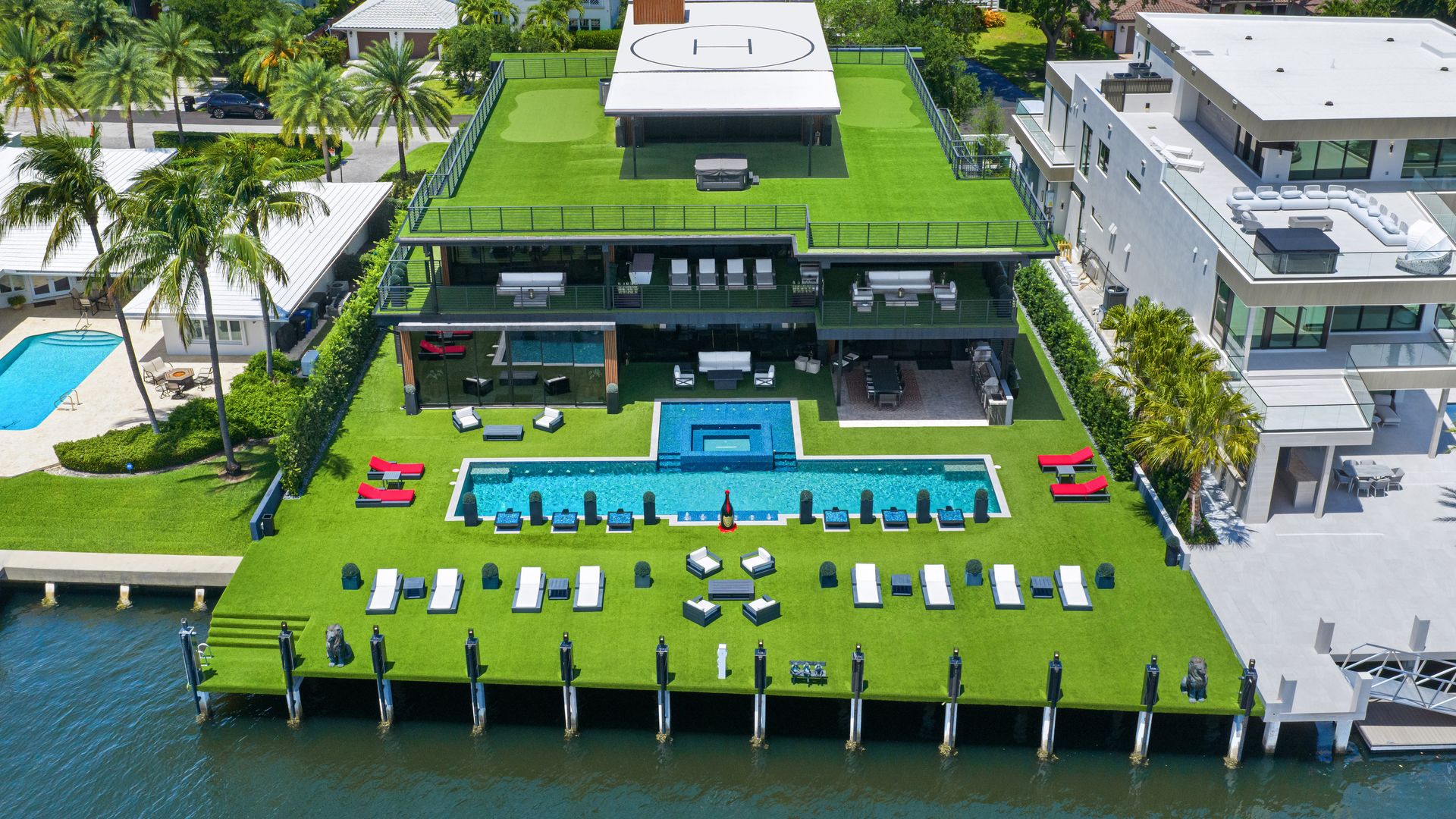 Aerial photo of backyard of waterfront, three-story modern Fort Lauderdale mansion with a private helipad on the roof.