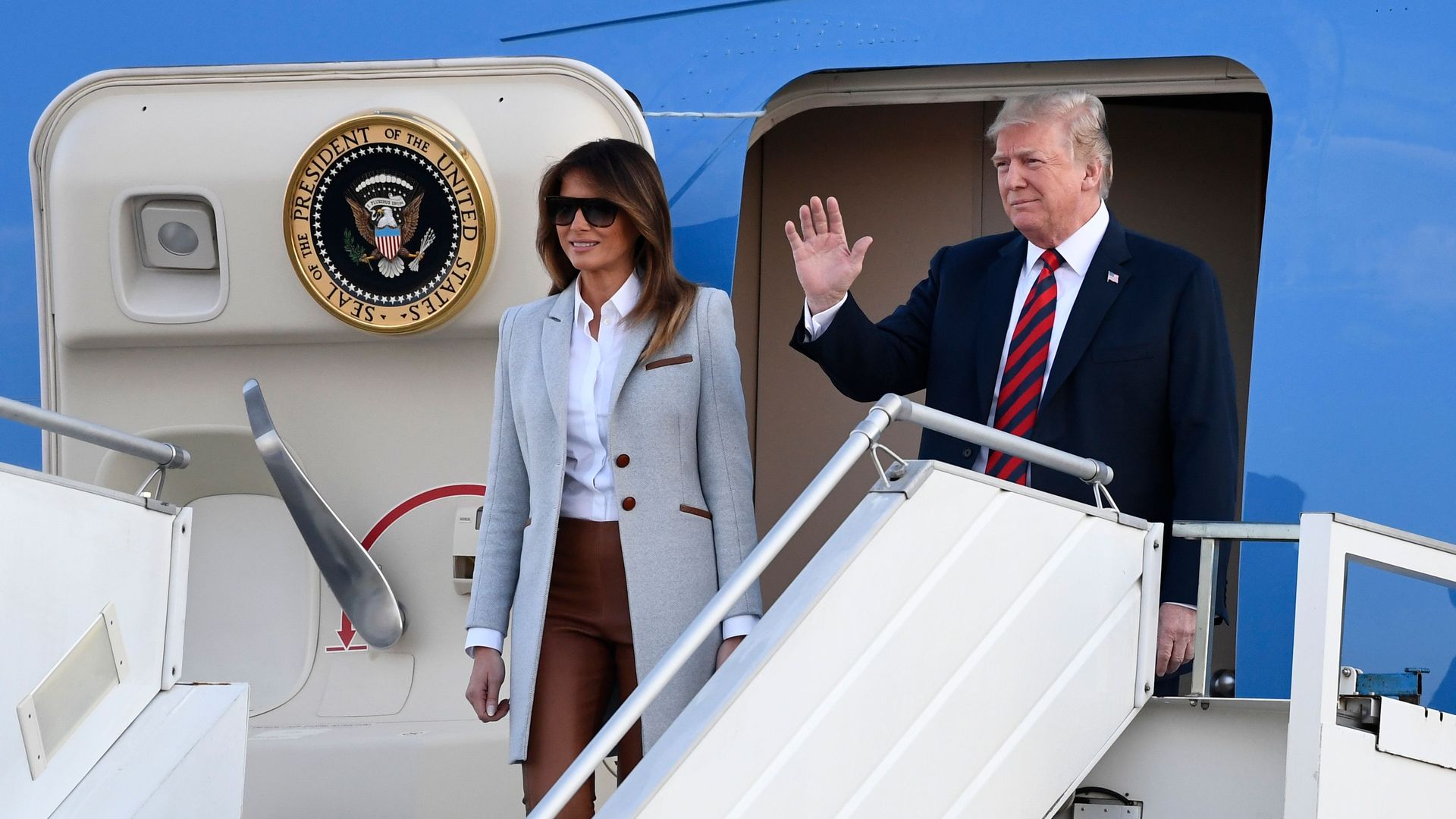 Melania and Trump on Air Force One staircase waving.