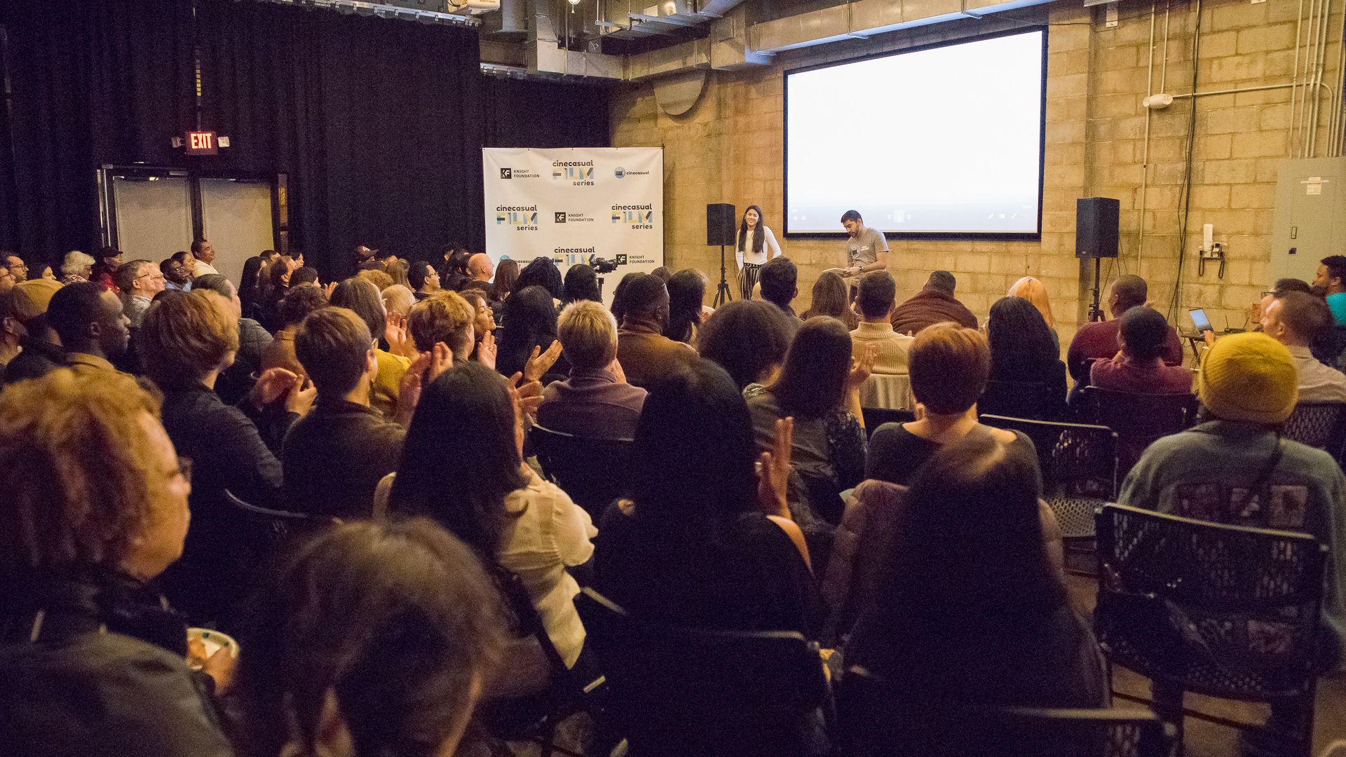 theater room packed with people starring at a projector screen