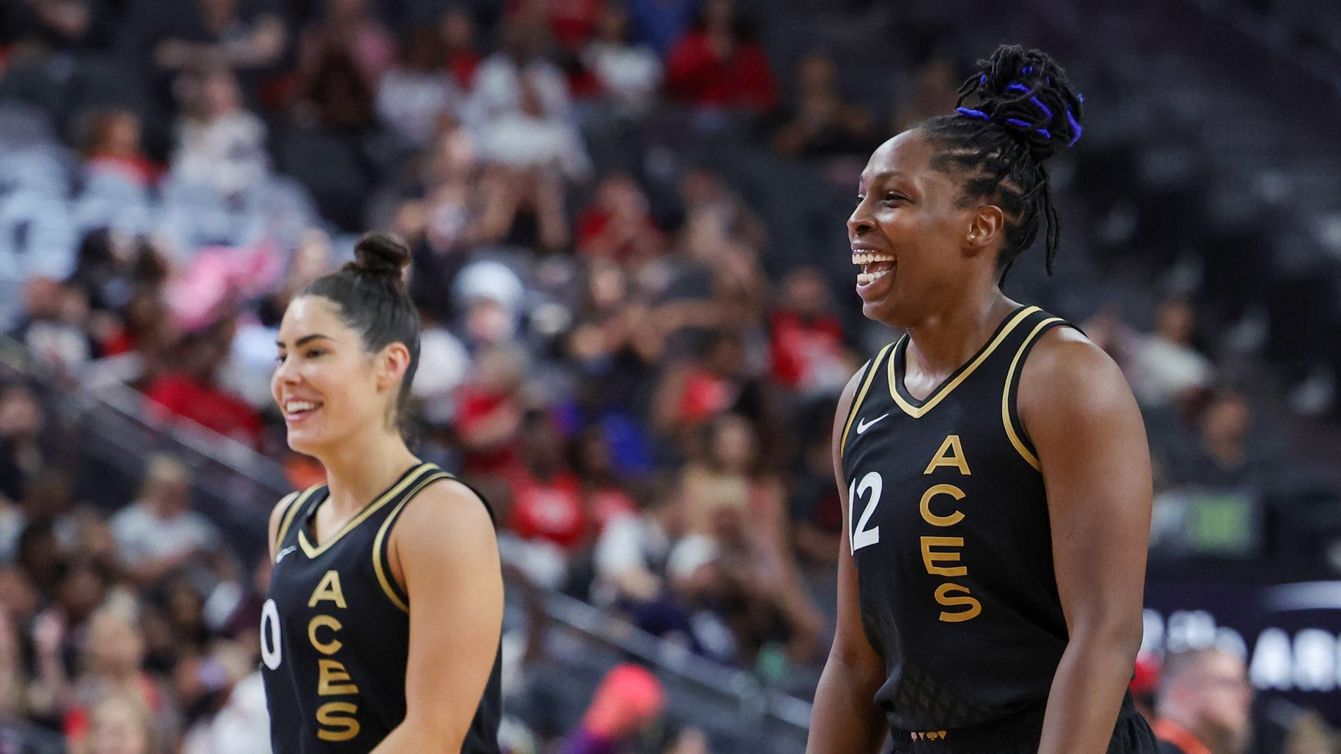 Two women in black basketball uniforms smiling next to each other