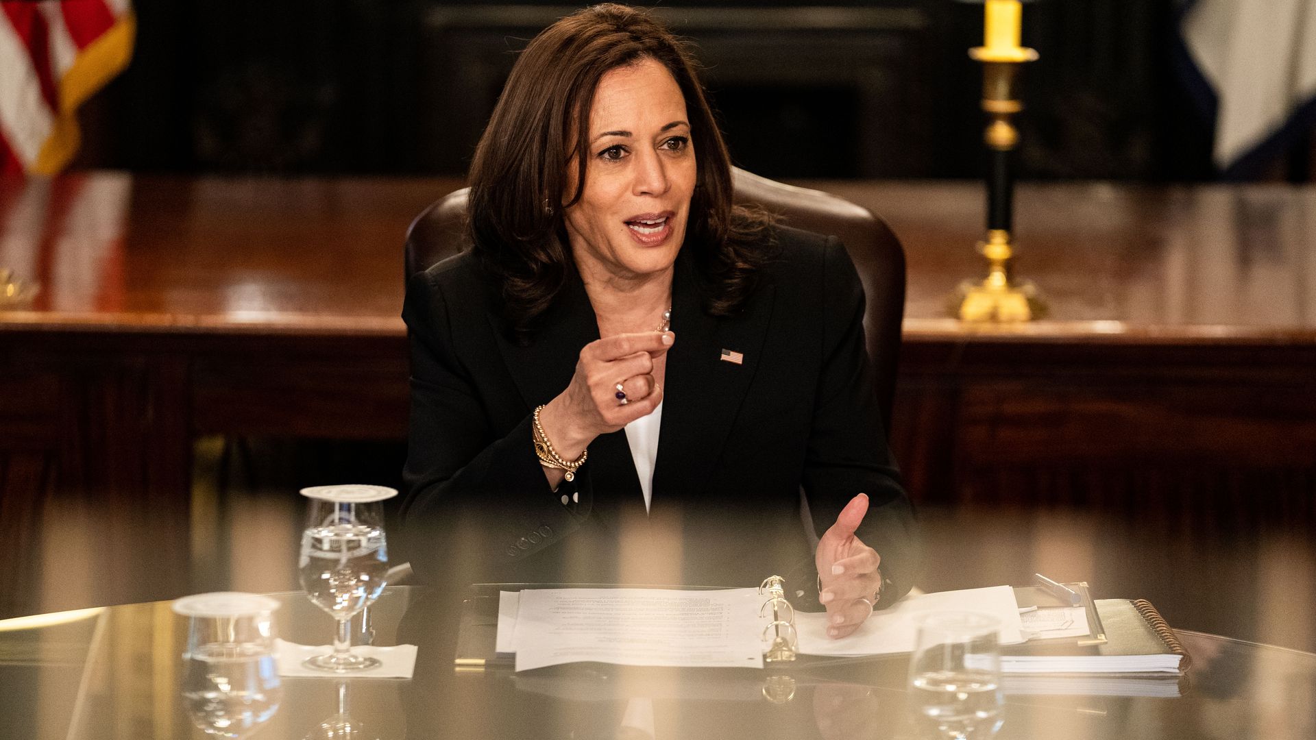 Photo of Kamala Harris sitting down at a table and speaking with one hand raised