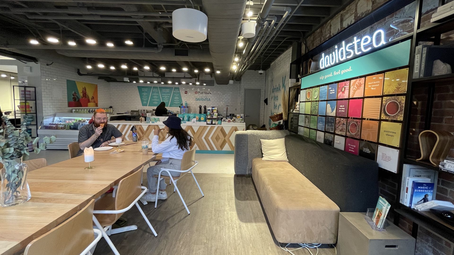 Two people sit at a long table inside a DavidsTea pop-up location, located on the second floor above the Lululemon on Newbury Street.