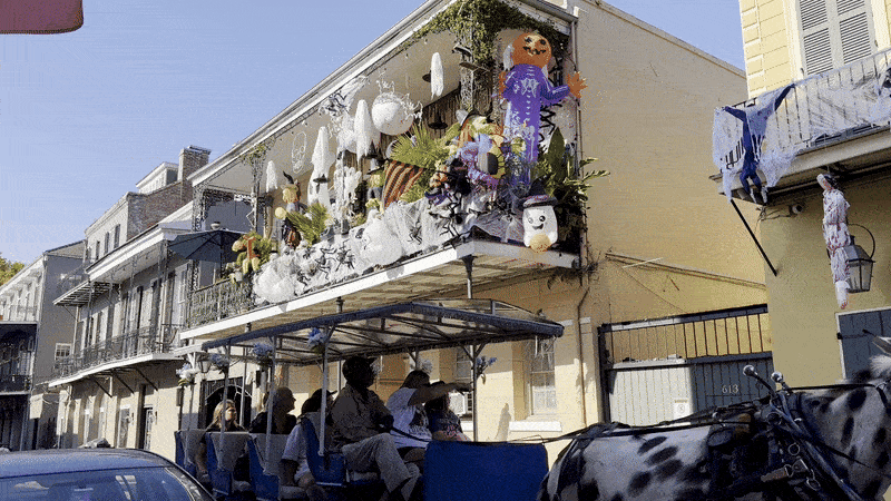 Photos shows a balcony covered in inflatables in the French Quarter with a carriage going by.