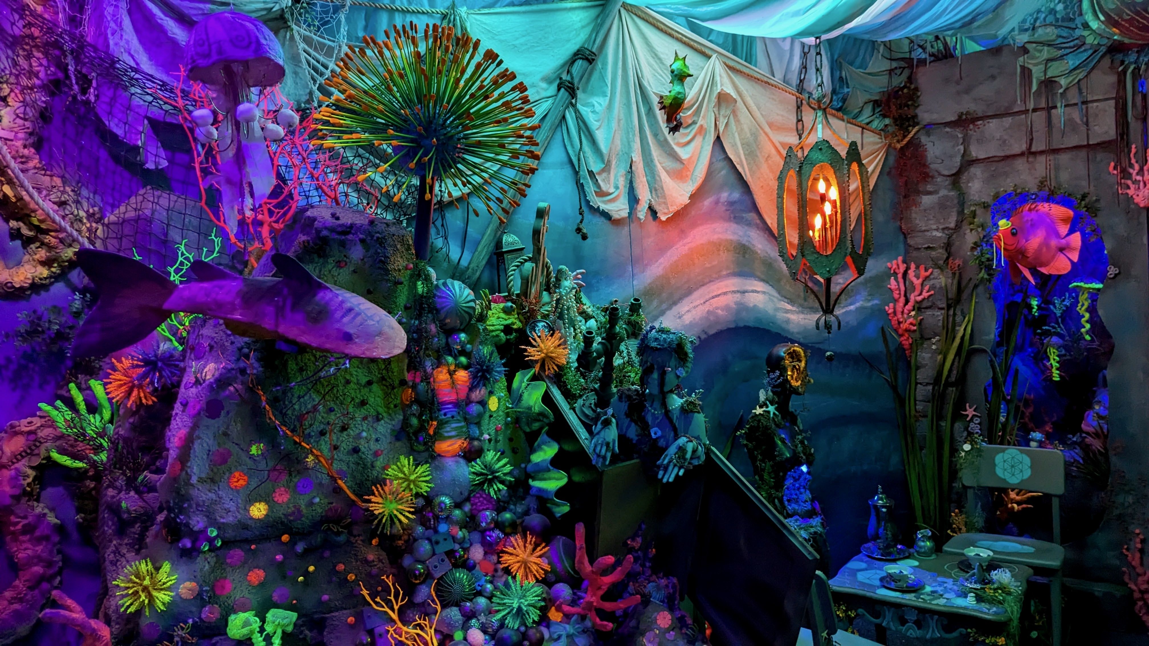 An undersea scene in an immersive art exhibit, with fish, coral and a cave