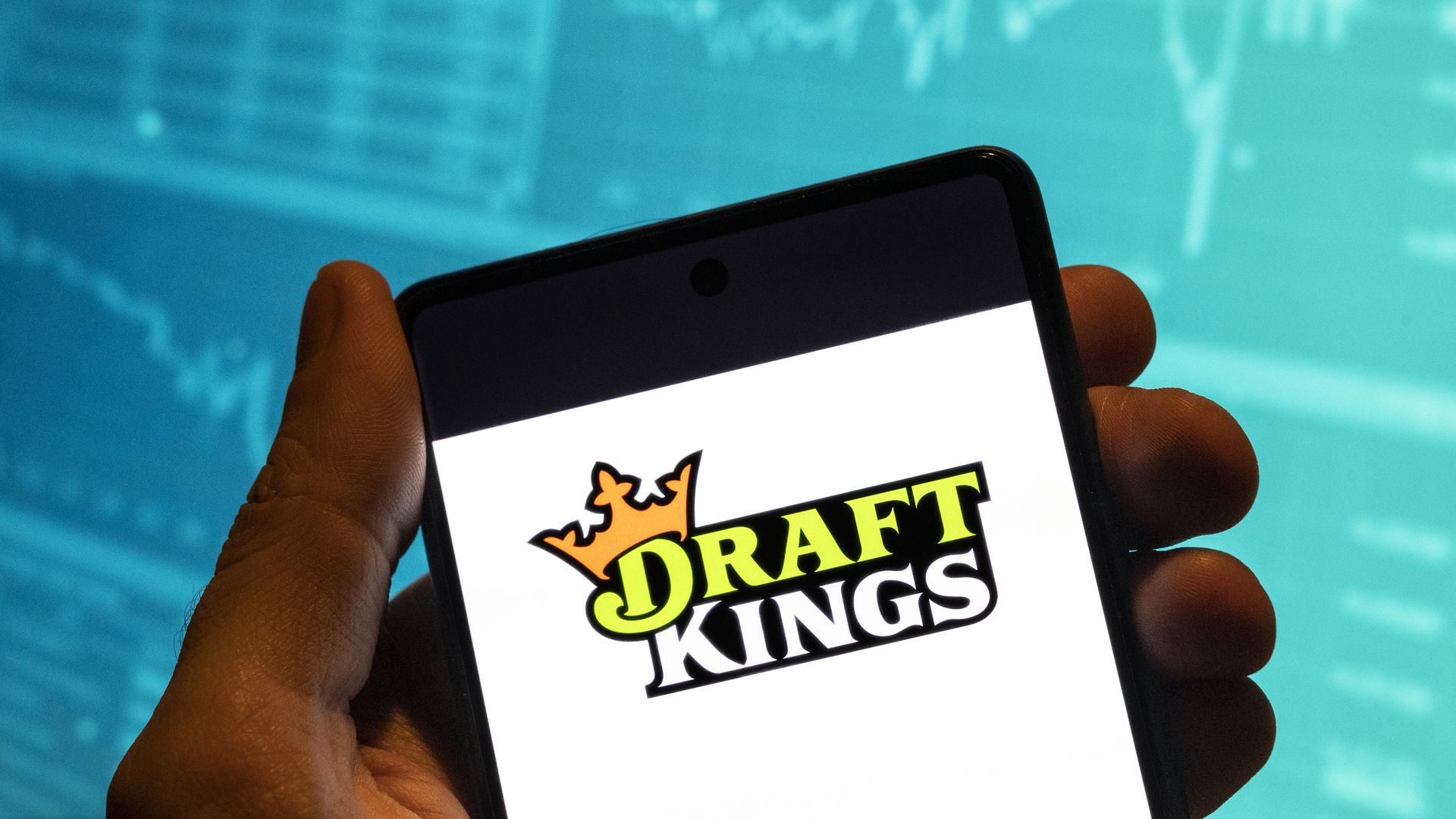 Someone holds up their phone to show the DraftKings loading screen. Boston-based DraftKing is one of several licensees in Massachusetts.