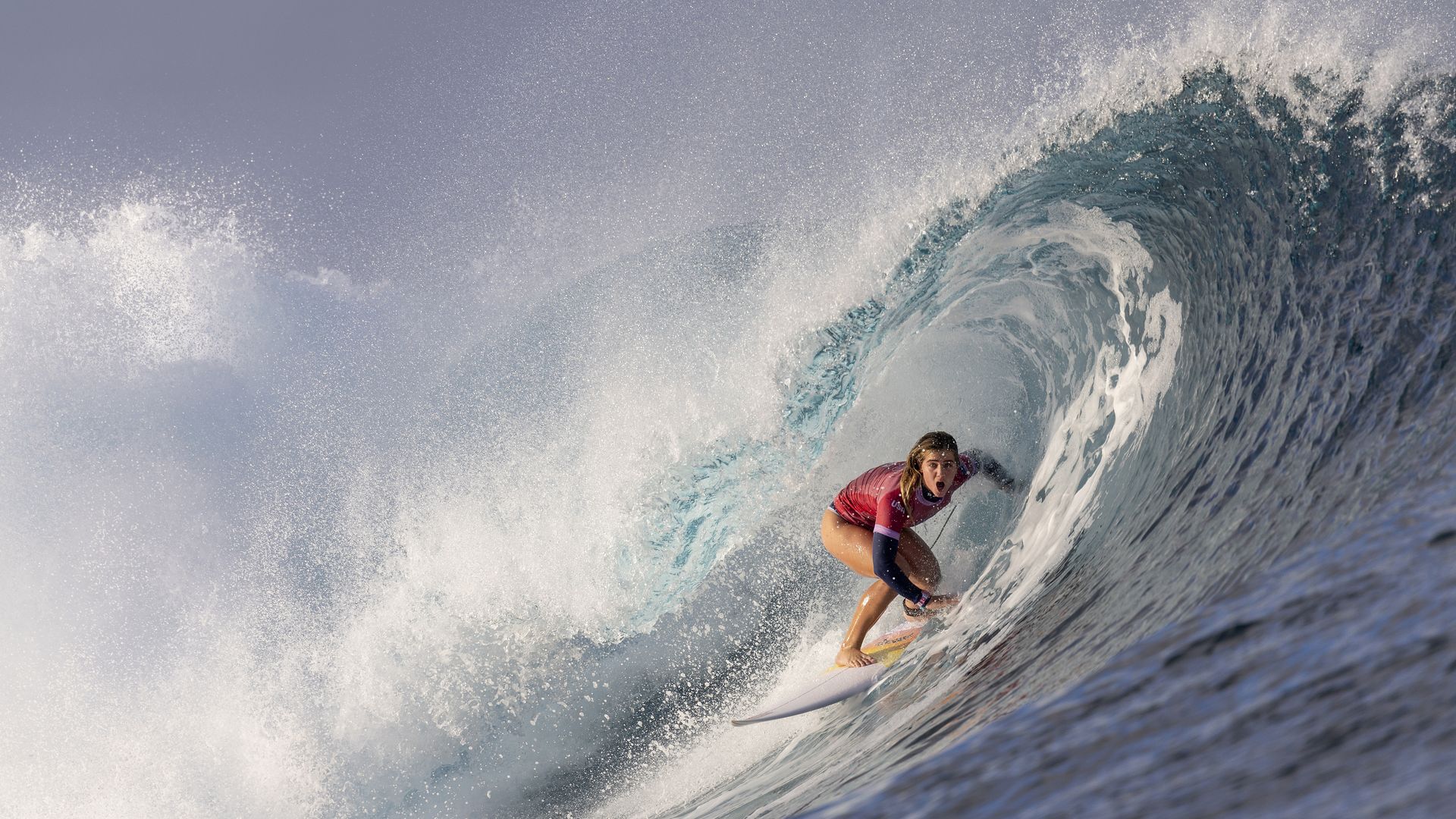 A female surfer riding a wave at the Olympics.