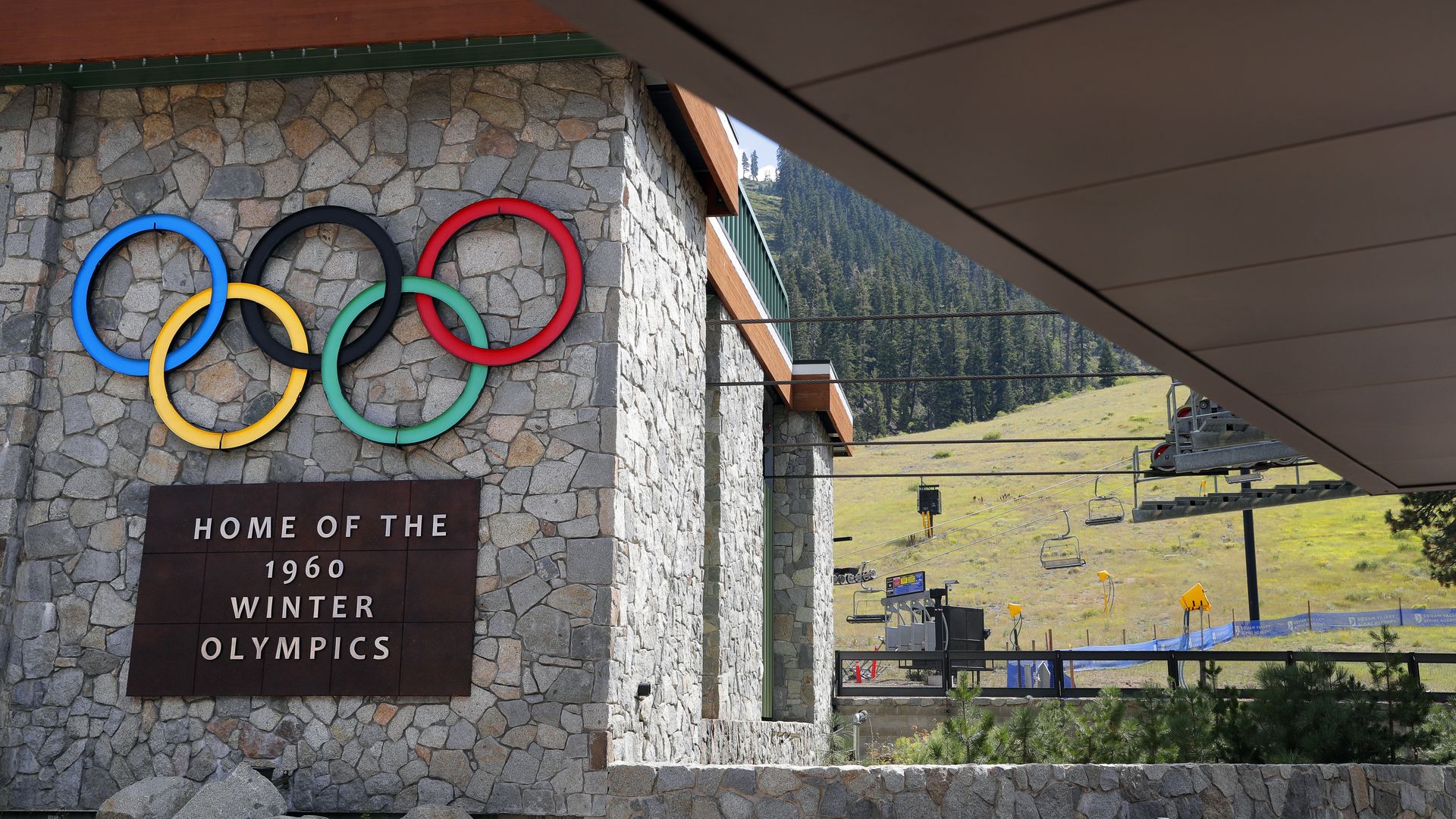Photo of a ski resort's roller coaster lift with the Olympic rings emblazoned on the building and a sign that says "Home of the 1960 Winter Olympics"