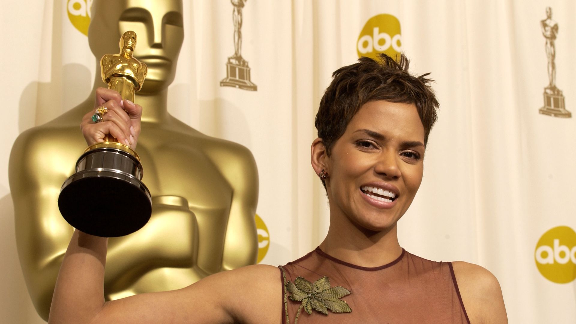 Halle Berry holds up her 2022 Academy Award on the red carpet.