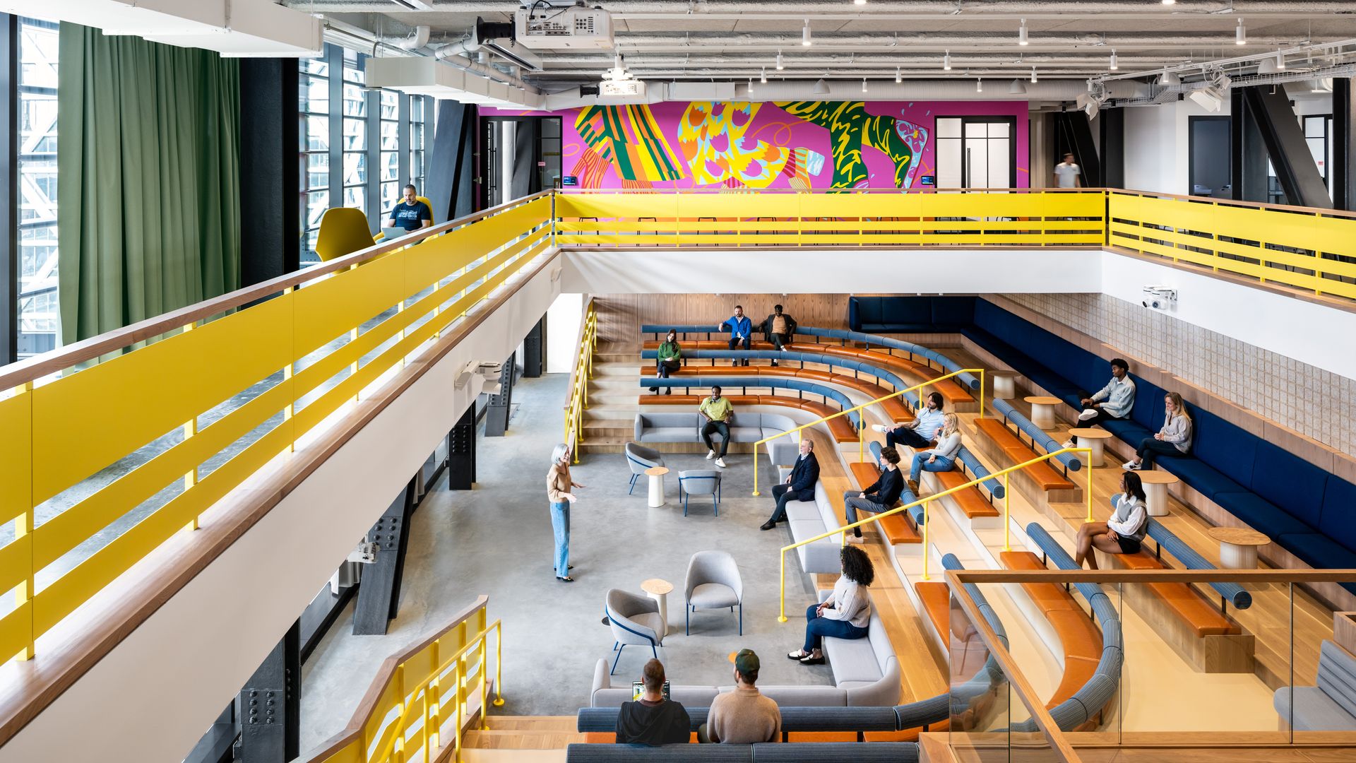 A sunken amphitheater in a light-filled space with yellow hand rails surrounding the space