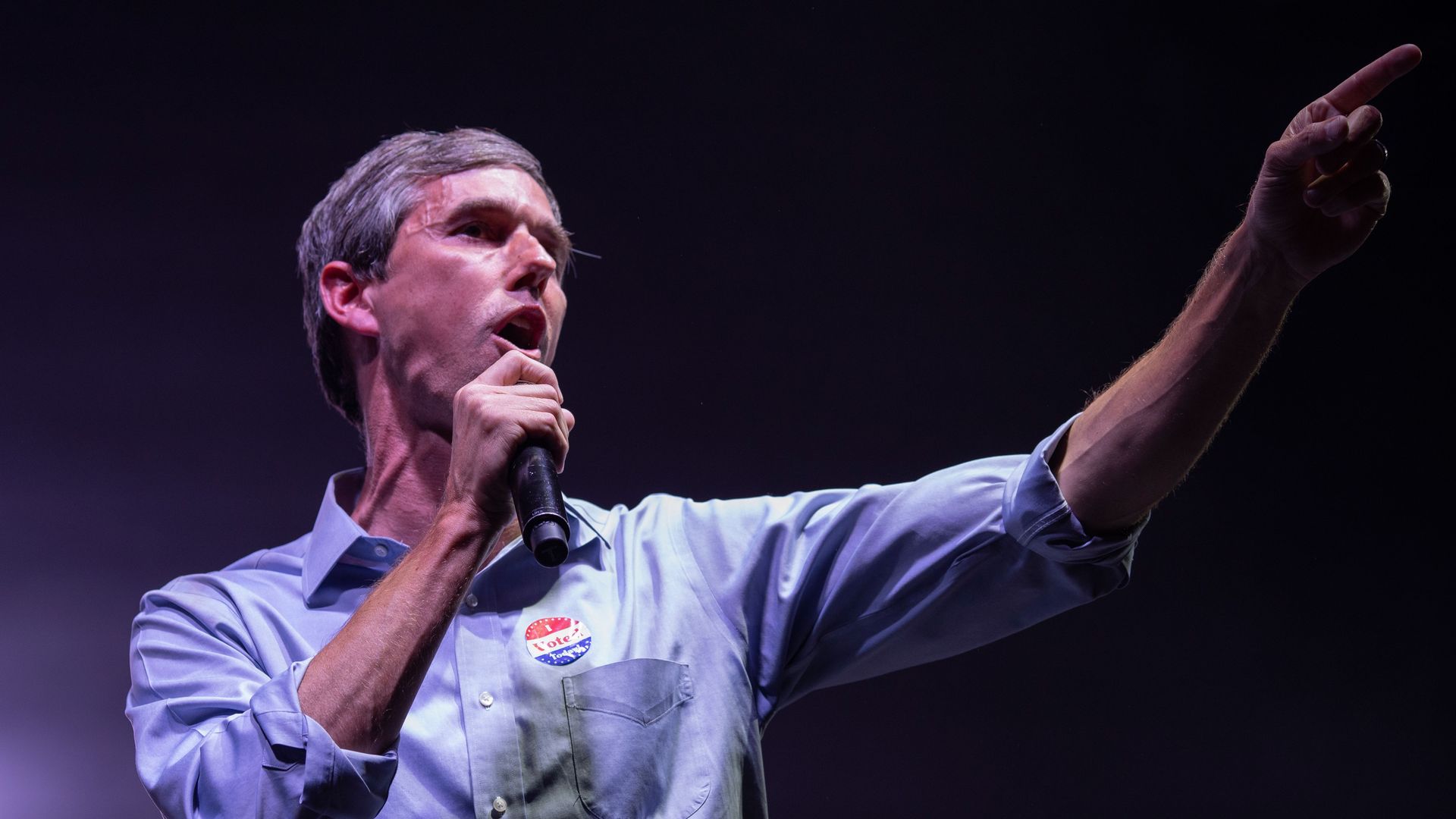 Beto O'Rourke standing on stage with a microphone in his hand