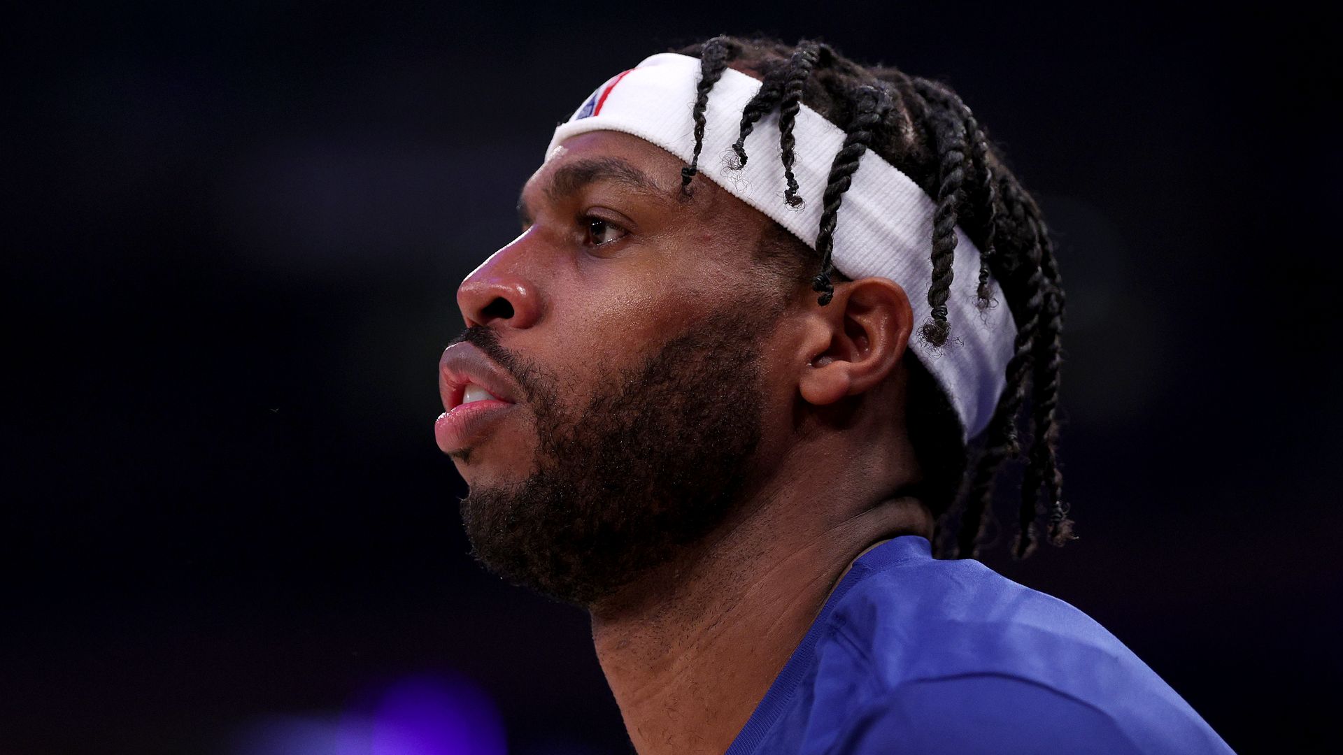 A black man with a white headband and braids