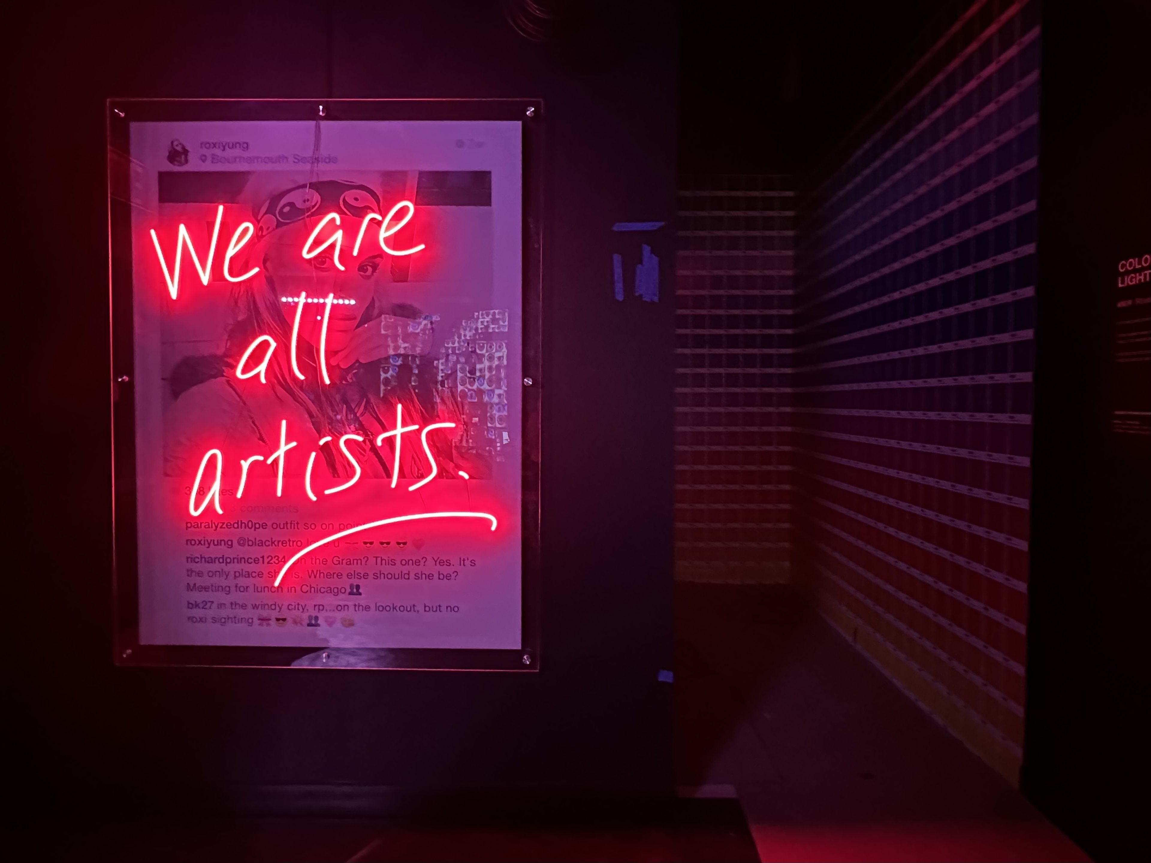 A blown up Instagram post by a model, with a comment by artist Richard Prince and a comment meant to portray WNDR Museum founder Brad Keywell. Neon graffiti appears over the post, saying "we are all artists."