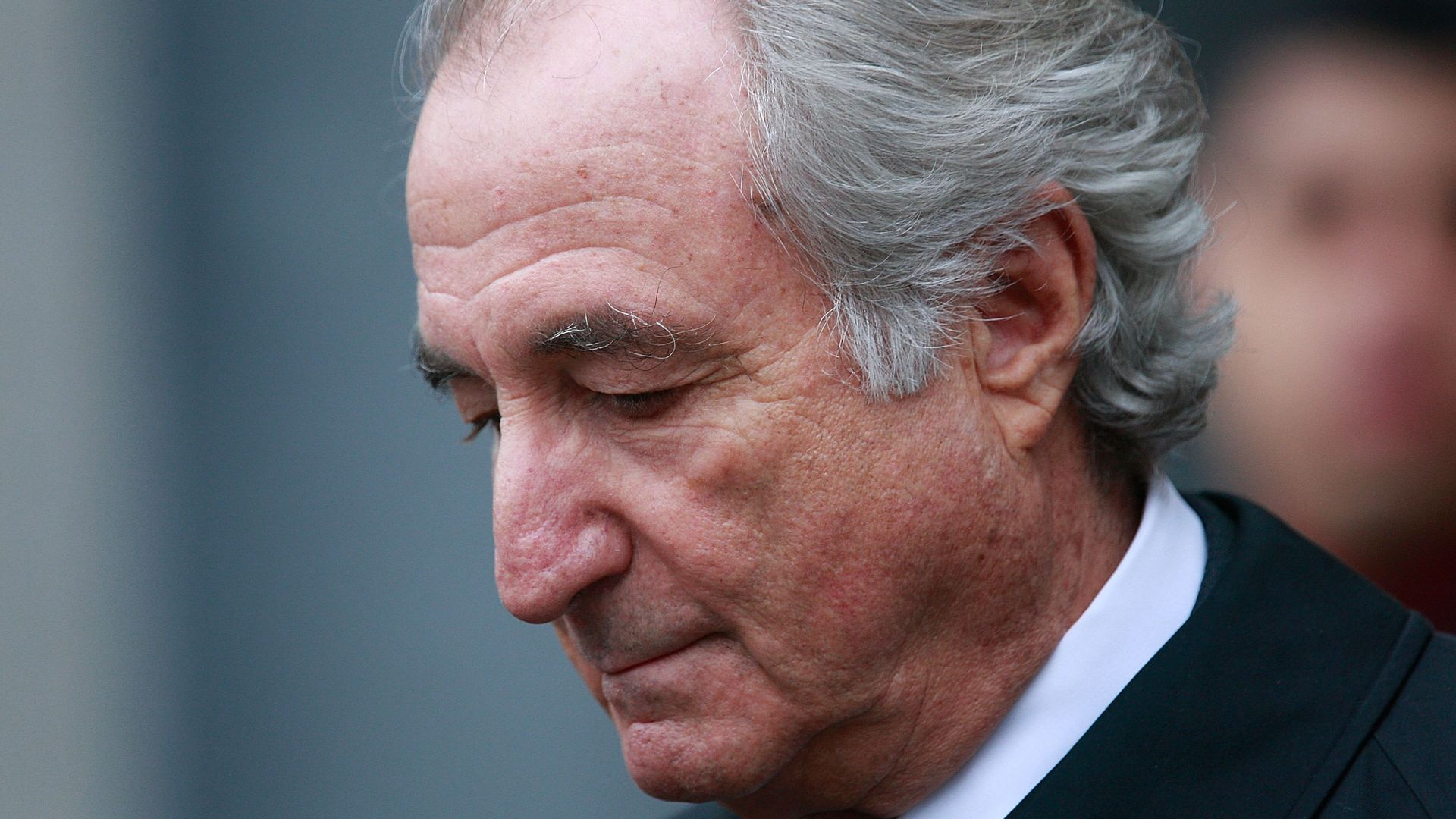 The profile of an older looking man with his eyes downcast. 