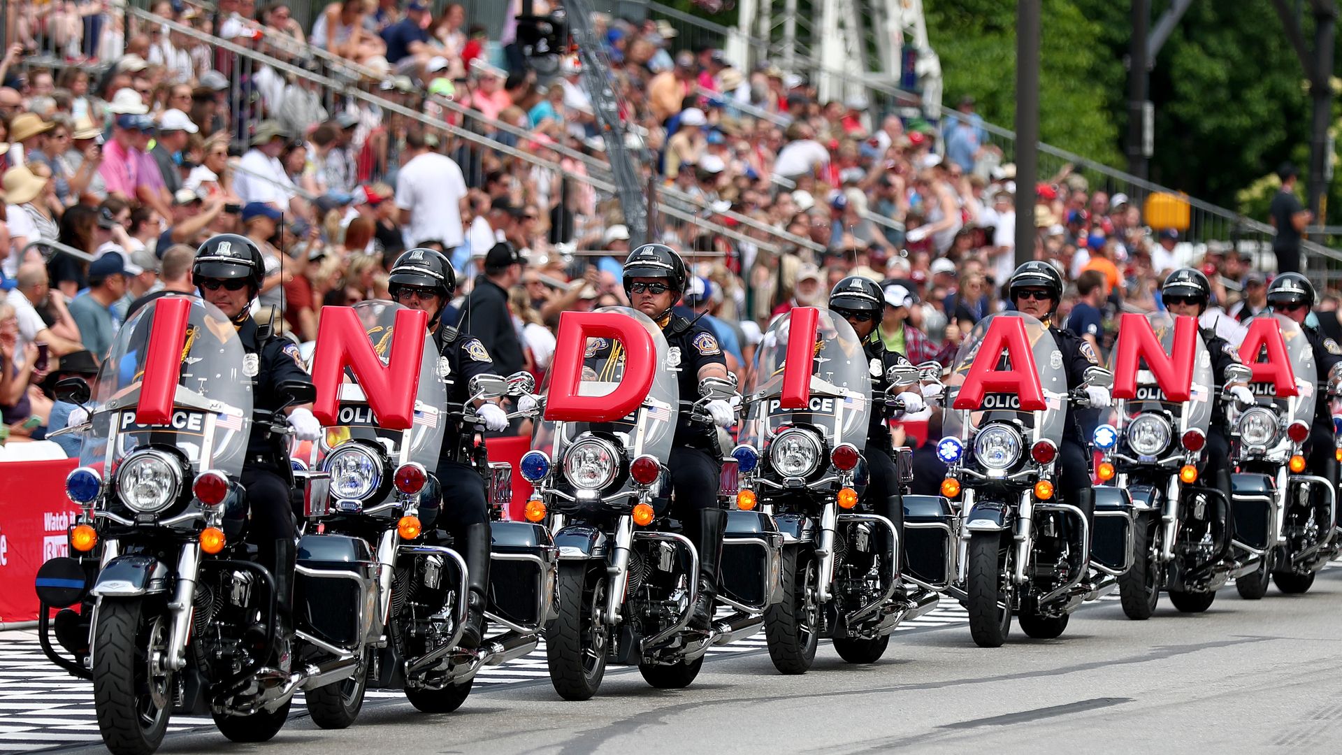 A line of motorcycles in a parade that spell out Indiana