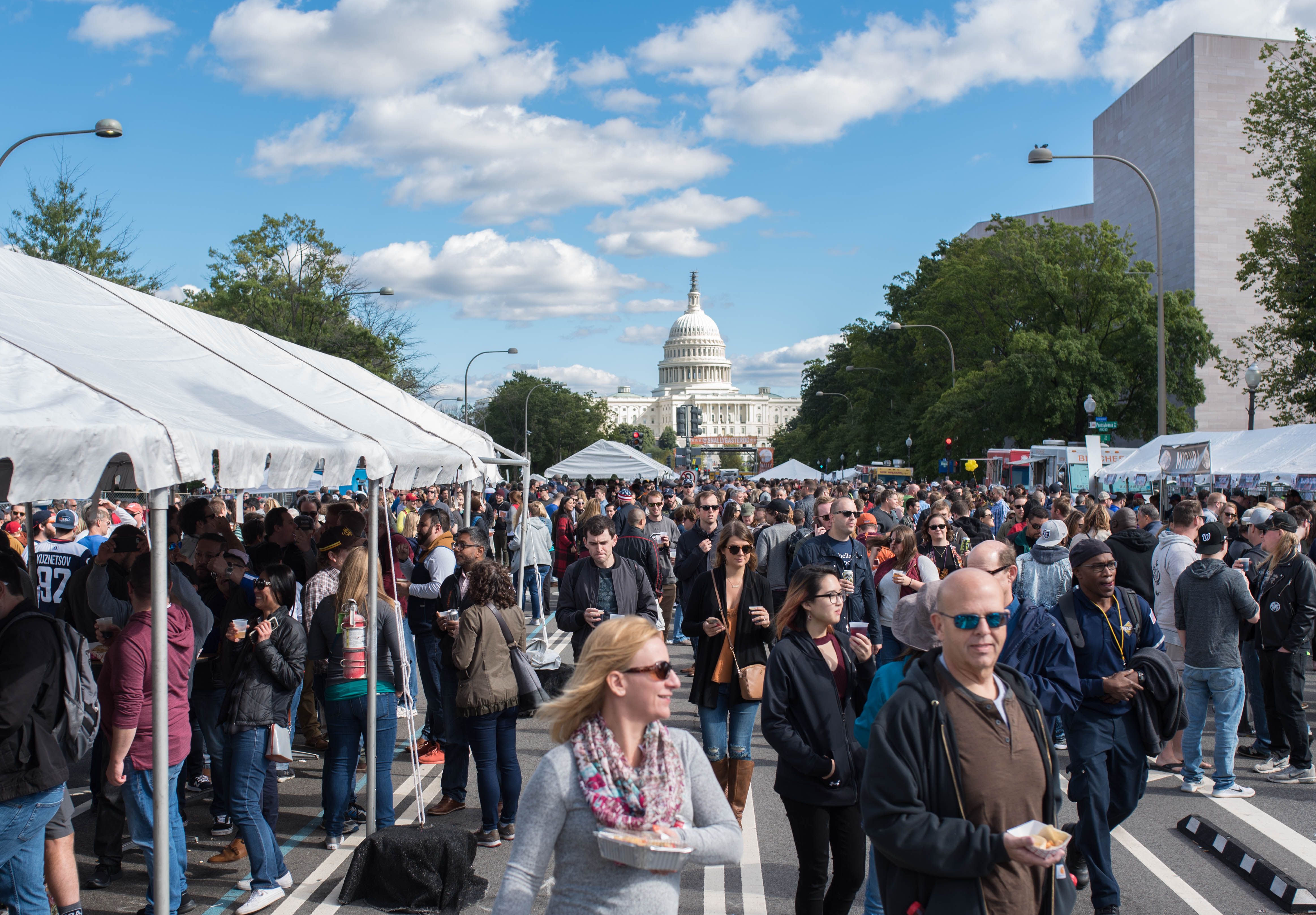 A crowd of people among tents with the Capitol Building in the background 