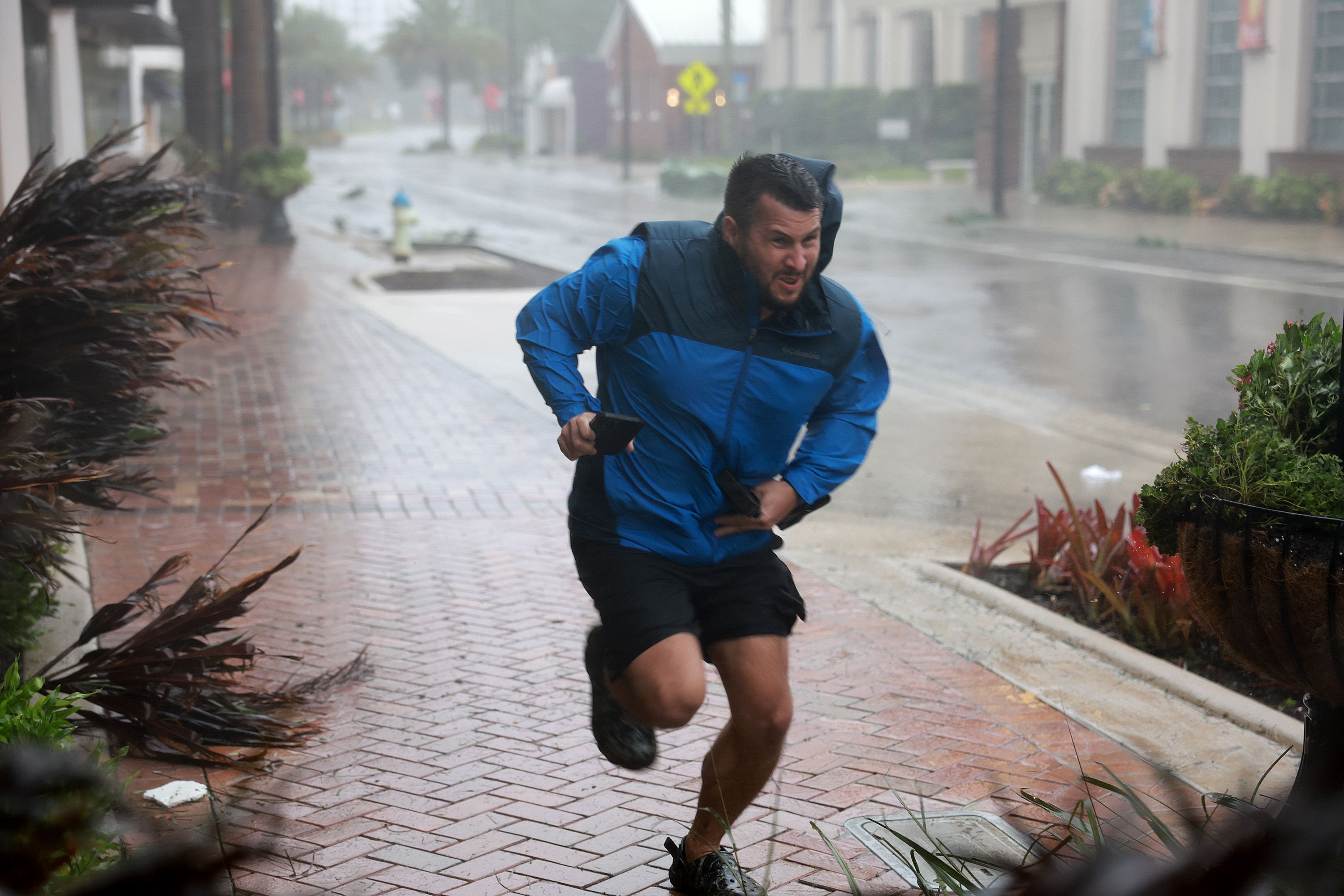 A man runs to a sheltered spot through the wind and rain from Hurricane Ian on September 28, 2022 in Sarasota, Florida.