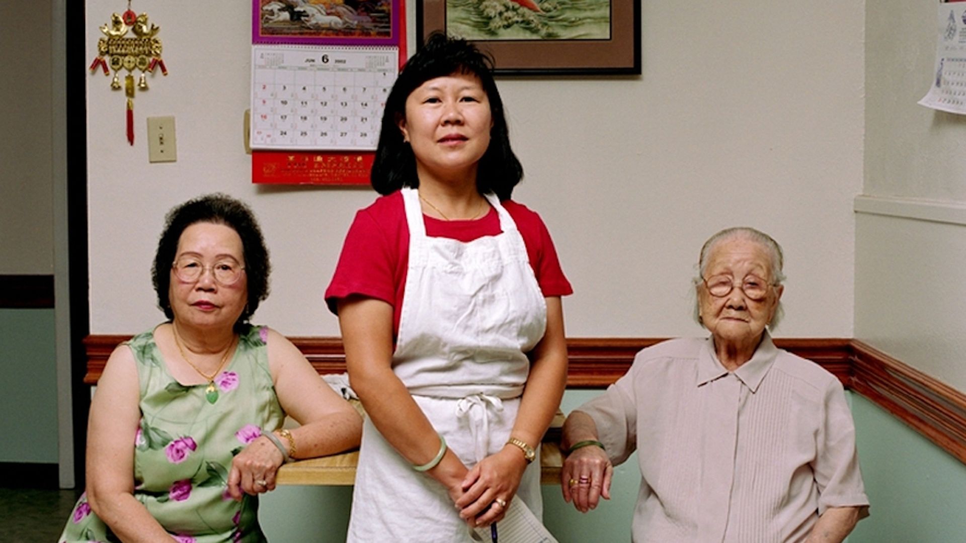 An image of three generations of women, one of which is wearing an apron.