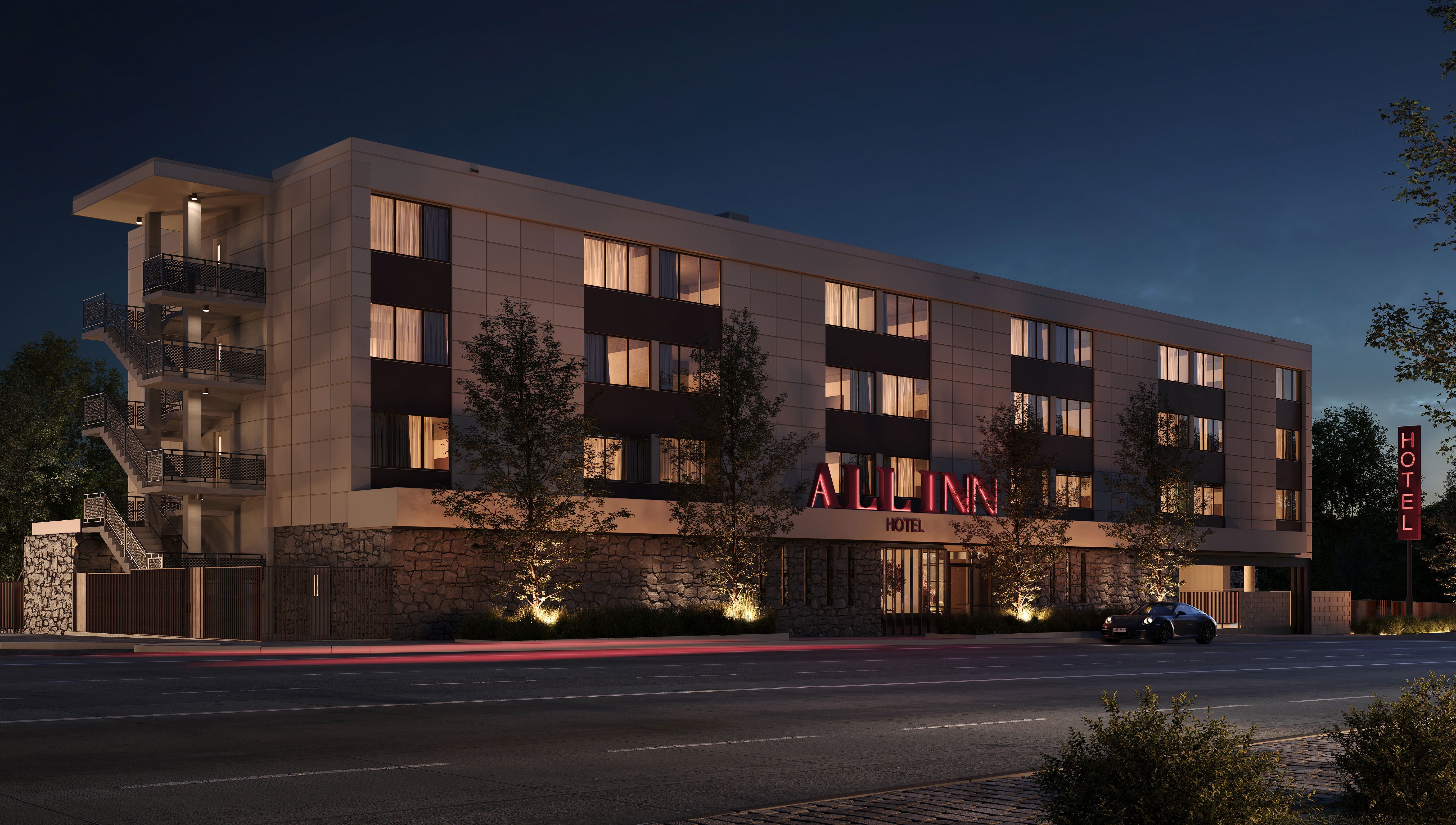 Nighttime exterior of a modern four-story hotel with a stone base and warm windows. A red neon ALL INN sign; a car on the street; vertical HOTEL sign on the right; left metal fire escape.