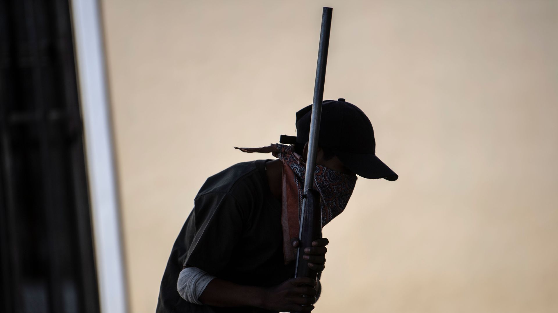 A silhouette of a boy holding a rifle 